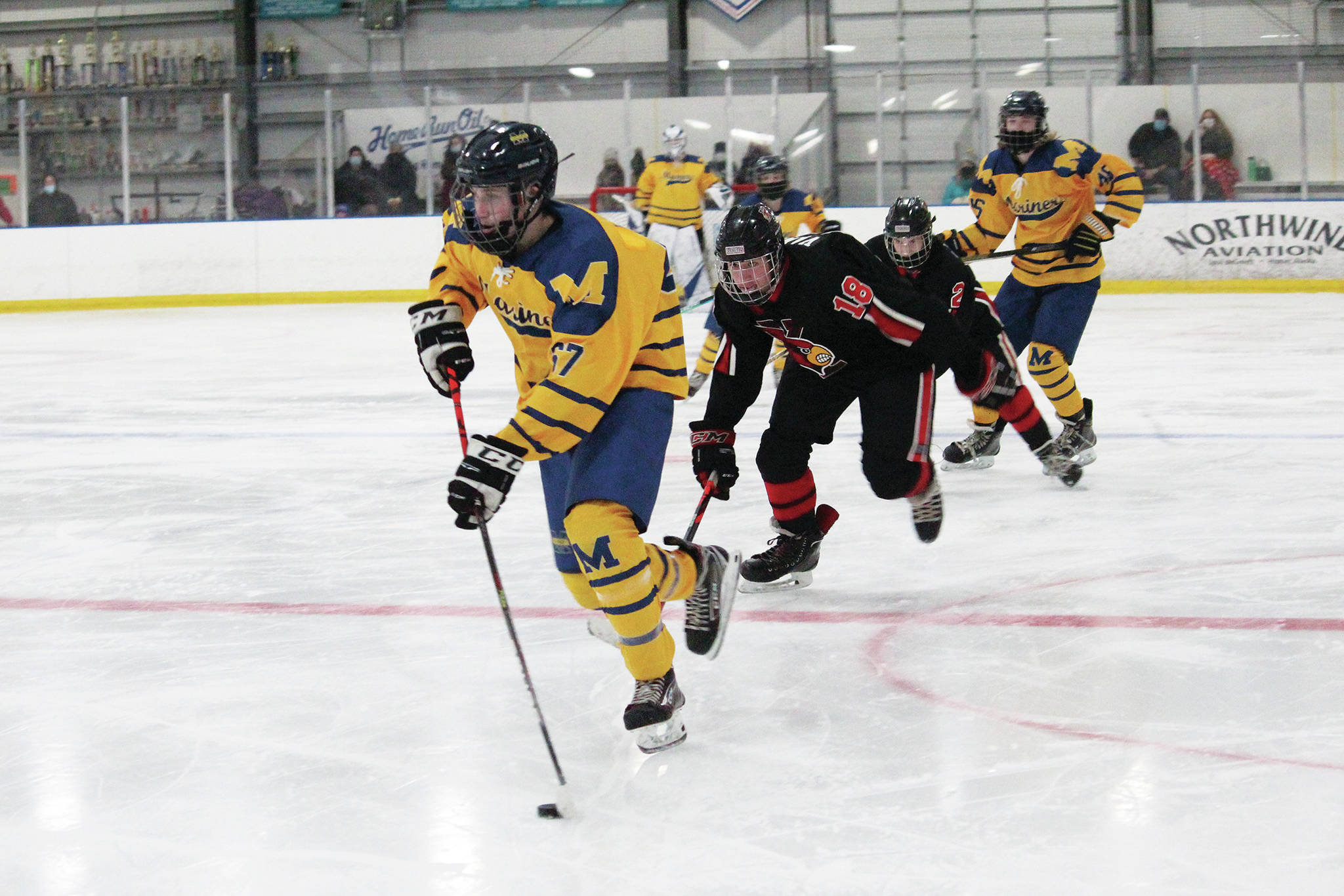 Homer’s Matfey Reutov takes the puck into Kardinal territory with Kenai players in pursuit during a Friday. Jan. 22, 2021 hockey game at Kevin Bell Arena in Homer, Alaska. (Photo by Megan Pacer/Homer News)