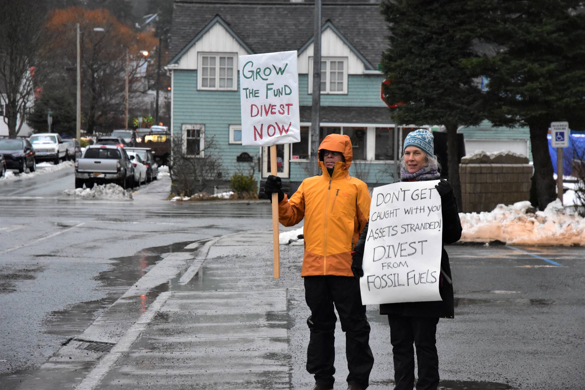Dick Farnell, right, and Suzanne Cohen of environmental group 350Juneau hold signs outside the Alaska Permanent Fund Corporation building during APFC’s Board of Directors quarterly meeting on Wednesday, Feb. 19, 2020. (Peter Segall / Juneau Empire File)