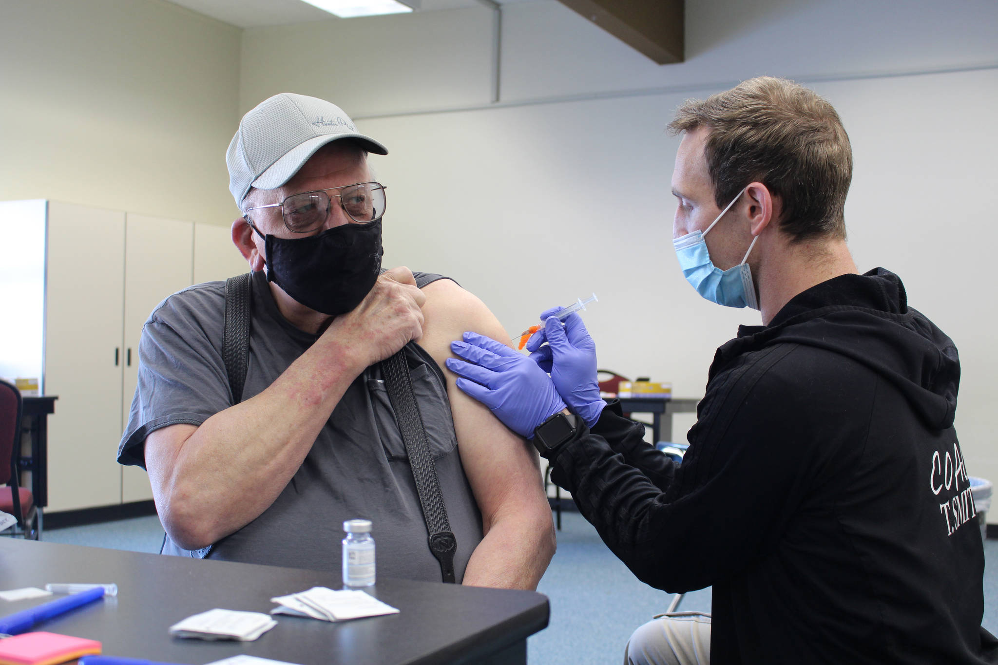 Ty Smith, paramedic/firefighter with the Nikiski Fire Department, administers the first dose of the Moderna COVID-19 vaccine to Ronald Huntsman of Nikiski during a clinic at the Nikiski Community Recreation Center on Jan. 30, 2021. (Photo by Brian Mazurek/Peninsula Clarion)