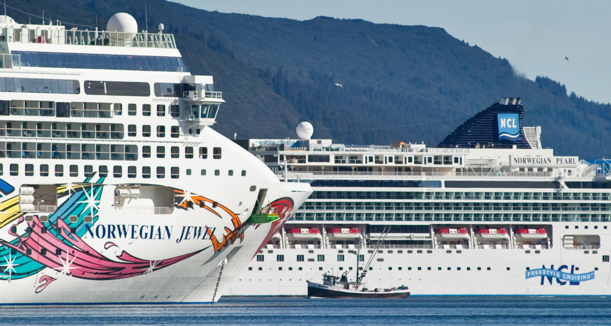 Michael Penn / Juneau Empire File
A fishing vessel is drawfed by the Norwegian Cruise Lines’ Norwegian Jewel and Norwegian Pearl in Juneau’s downtown harbor in September 2014. On Thursday, Canada announced a ban on cruise vessels in Canadian waters through February 2022.