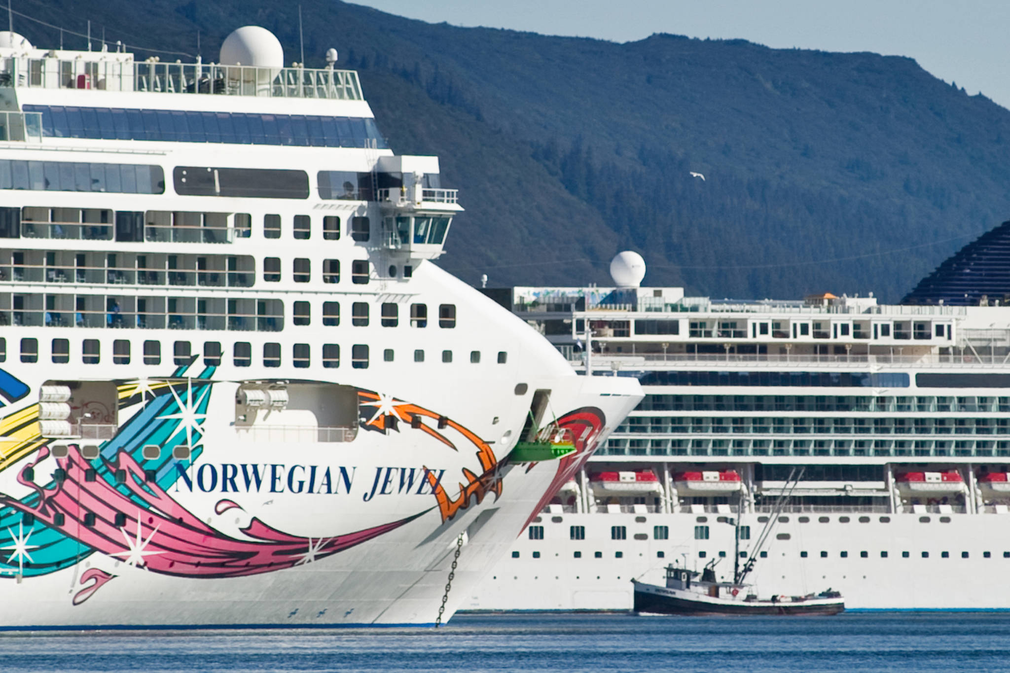 A fishing vessel is drawfed by the Norwegian Cruise Lines' Norwegian Jewel and Norwegian Pearl in Juneau's downtown harbor in September 2014. On Thursday, Canada announced a ban on cruise vessels in Canadian waters through February 2022. (Michael Penn / Juneau Empire File)