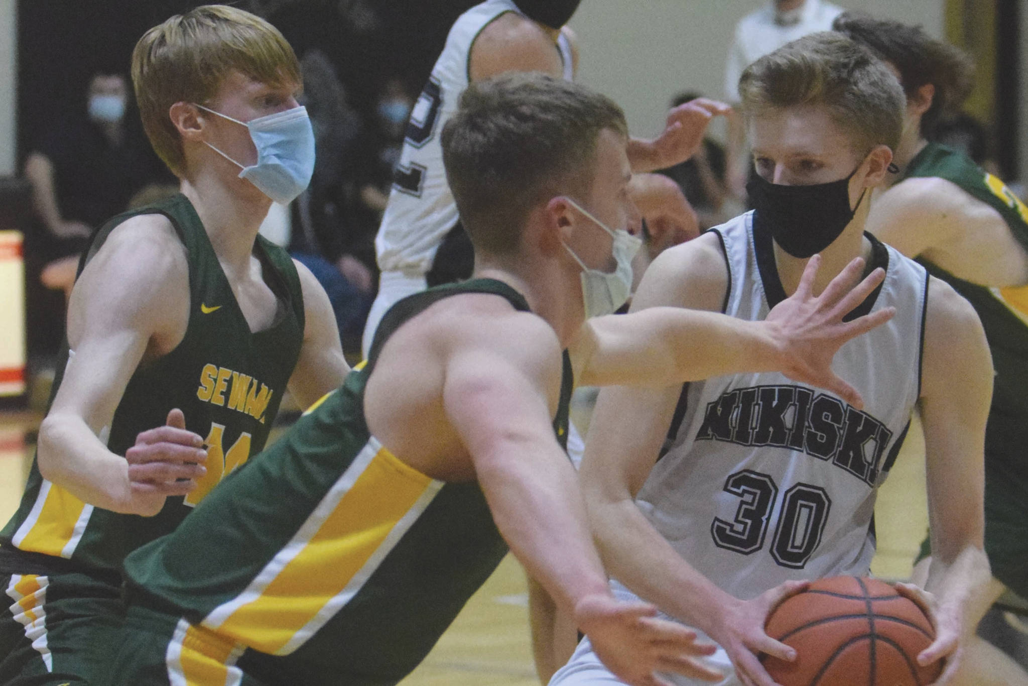 Nikiski's Austin Stafford drives on Seward's Max Pfeiffenberger and Trey Ingalls on Tuesday, Feb. 9, 2021, at Nikiski High School in Nikiski, Alaska. (Photo by Jeff Helminiak/Peninsula Clarion)