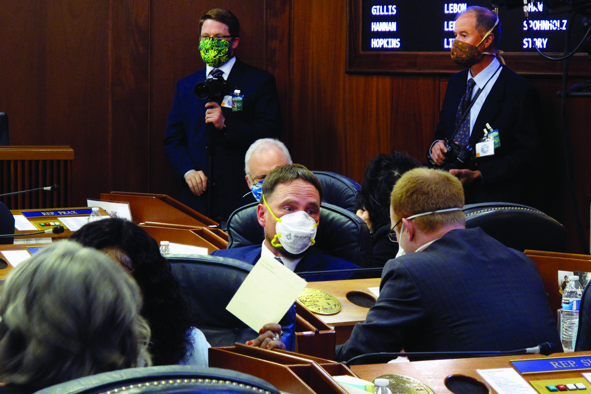 Alaska state Rep. Ben Carpenter, center, speaks to Rep. David Eastman on the floor of the House on Monday, May 18, 2020, in Juneau, Alaska. (AP Photo/Becky Bohrer)