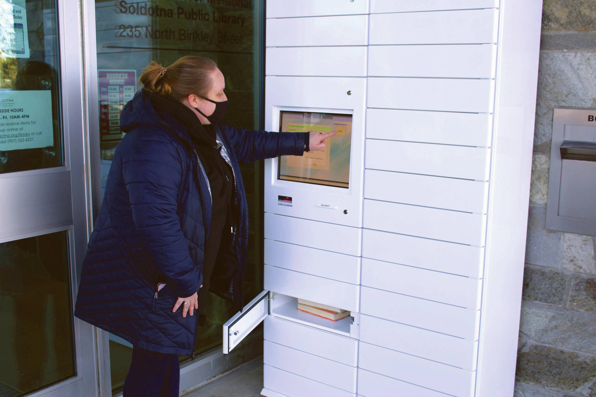Ryanna Thurman uses a holds locker at the Soldotna Public Library on Friday, Jan. 15 in Soldotna, Alaska. (Ashlyn O’Hara/Peninsula Clarion)