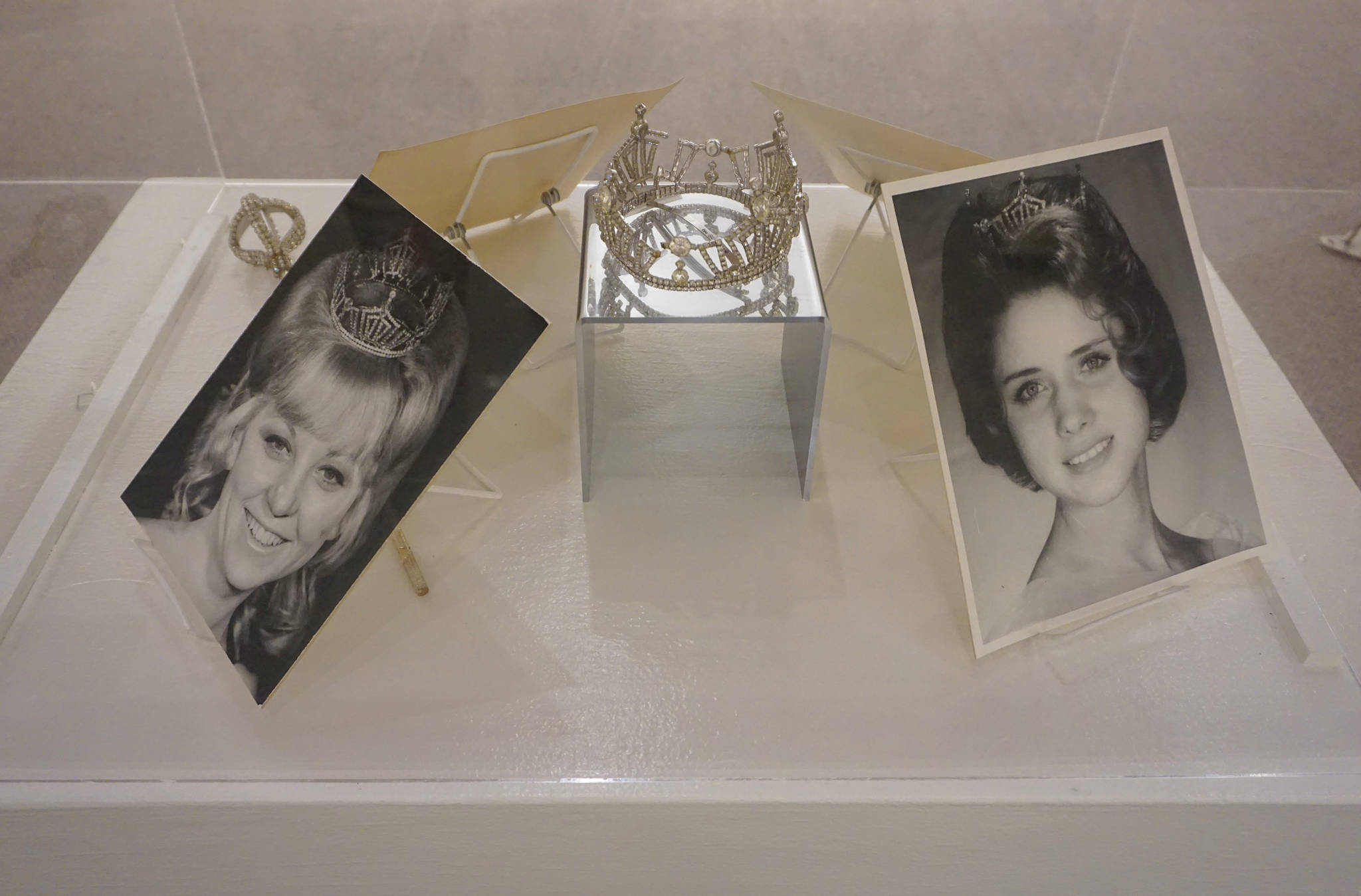 Two Homer Winter Carnival queens are shown in a display with the crown and scepter they carried during their reign. At left is Patricia Johnson, queen in 1969, and at right is Judy Johnson, queen in 1966. The photos are included in “Familiar Faces: Portrait of a Community,” on exhibit through May 2021 at the Pratt Museum in Homer, Alaska. (Photo by Michael Armstrong/Homer News)