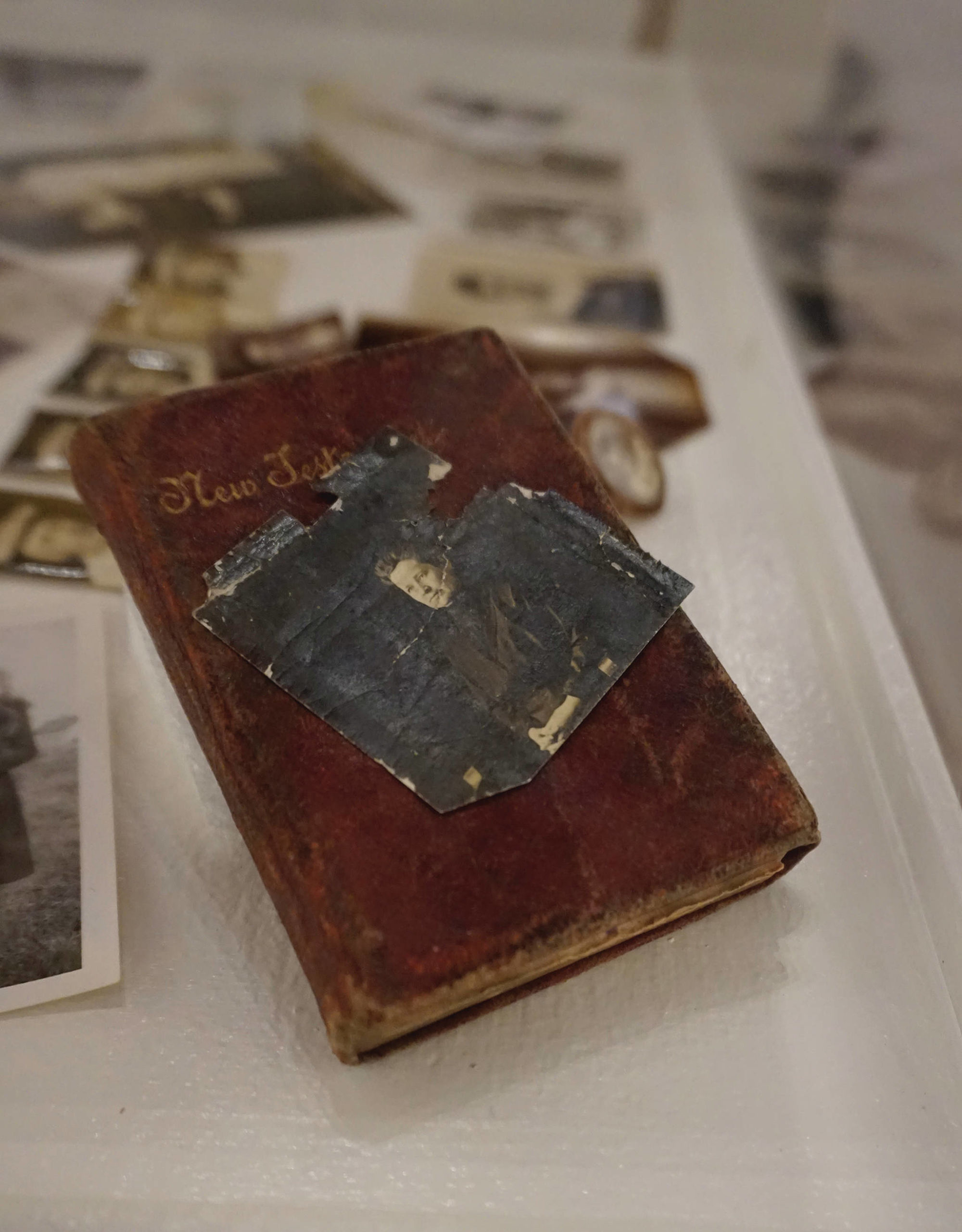 A portrait of Sam Pratt’s mother is shown on top of a New Testament she gave him in 1904. Pratt carried the Bible and photo while serving as a corporal in Company A, 9th Engineers, Mounted, during World War I. The Bible and photo are included in “Familiar Faces: Portrait of a Community,” on exhibit through May 2021 at the Pratt Museum in Homer, Alaska. (Photo by Michael Armstrong/Homer News)