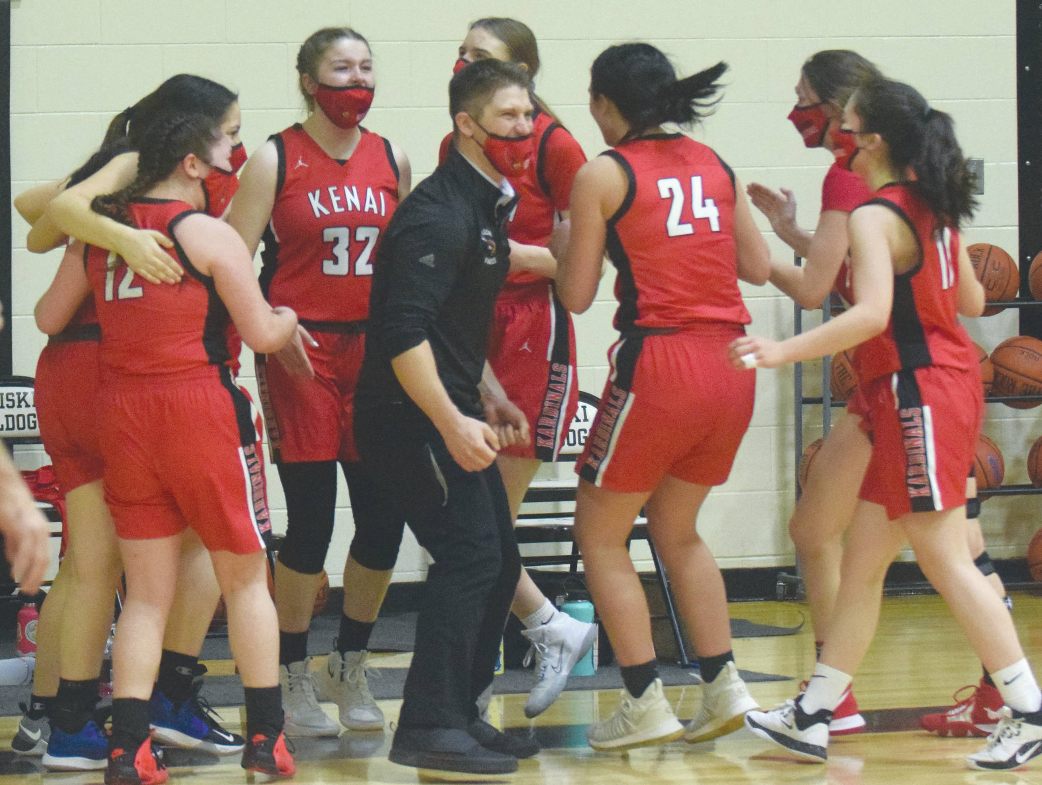 Head coach Jeff Swick and the Kenai Central girls basketball team celebrate earning a berth in the Class 3A state tounament after defeating Homer in the semifinals of the Southcentral Conference girls tournament Friday, March 12, 2021, at Nikiski High School in Nikiski, Alaska. (Photo by Jeff Helminiak/Peninsula Clarion)
