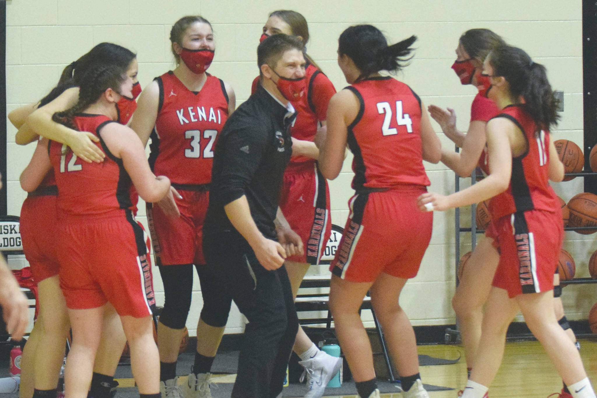 Head coach Jeff Swick and the Kenai Central girls basketball team celebrate earning a berth in the Class 3A state tounament after defeating Homer in the semifinals of the Southcentral Conference girls tournament Friday, March 12, 2021, at Nikiski High School in Nikiski, Alaska. (Photo by Jeff Helminiak/Peninsula Clarion)