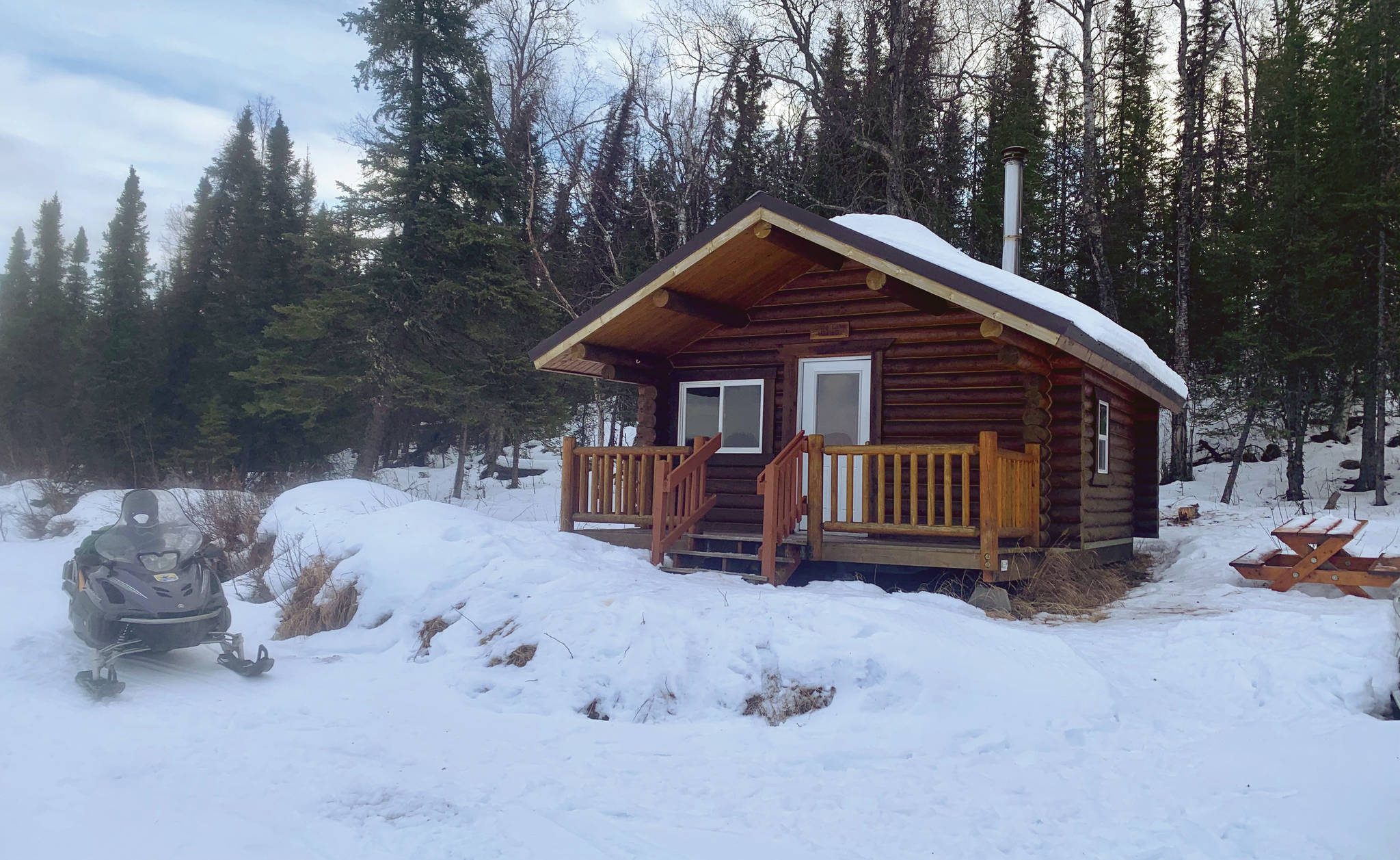 A snowmachine at rest in front of the Snag Lake public use cabin. (Photo provided by USFWS)