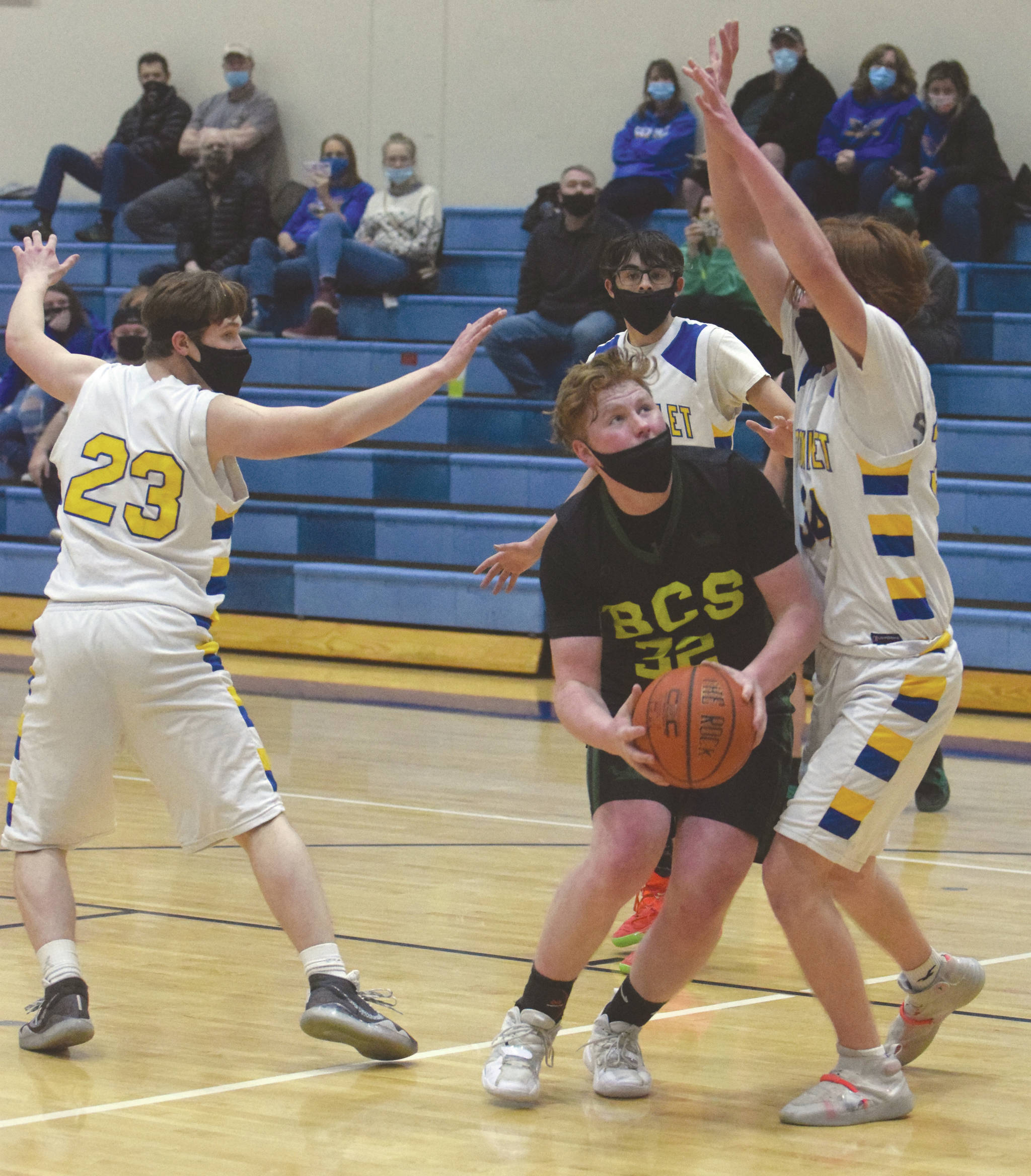 Birchwood Christian’s Jackson Hanson drives to the basket against Cook Inlet Academy’s Grizzly Beard and Mason Zeigler on Thursday, March 18, 2021, in the Peninsula Conference tournament at Soldotna High School in Soldotna, Alaska. (Photo by Jeff Helminiak/Peninsula Clarion)