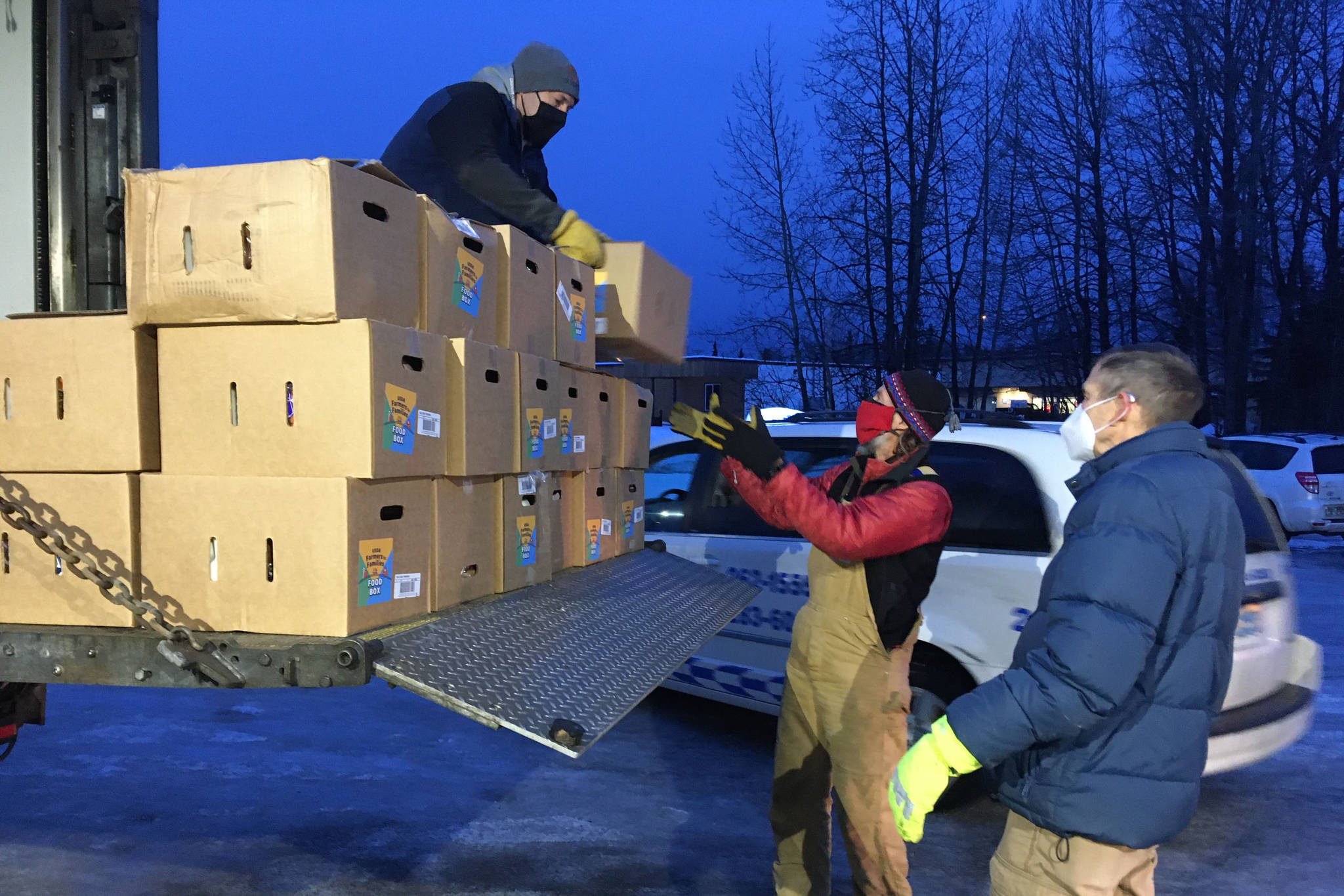 Todd Duwe hands a food box to Brad Nyquist as Mark Larson looks on Tuesday, Dec. 22, 2020, at Christ Lutheran Church in Soldotna, Alaska. The church volunteers were distributing food from the United States Department of Agricultures Farmers to Families Food Box Program, delivered by the Kenai Peninsula Food Bank. The food bank saw a surge in demand last year due to the coronavirus pandemic. (Photo by Jeff Helminiak/Peninsula Clarion)