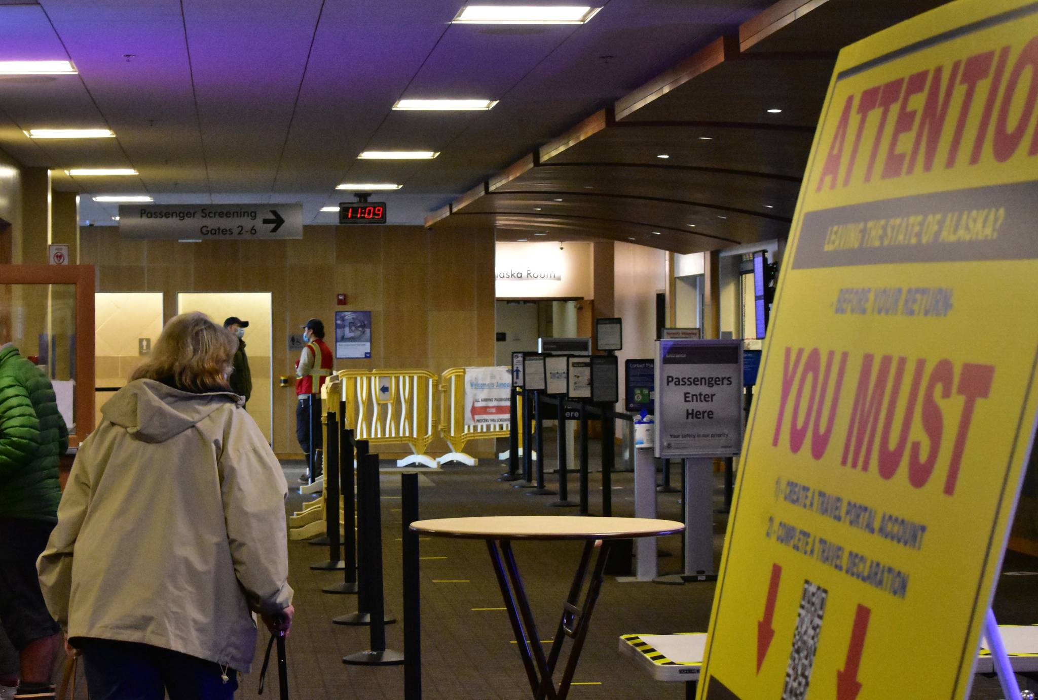 Passengers at the Juneau International Airport make their way past signage notifying the public about the state’s travel restrictions on Monday, Nov. 15, 2020. Alaska Department of Health and Social Services released a request for information seeking to determine interest among potential contractors to provide a one-dose vaccine to interested travelers in a secure section of the airports in Anchorage, Juneau, Fairbanks and Ketchikan. (Peter Segall / Juneau Empire File)