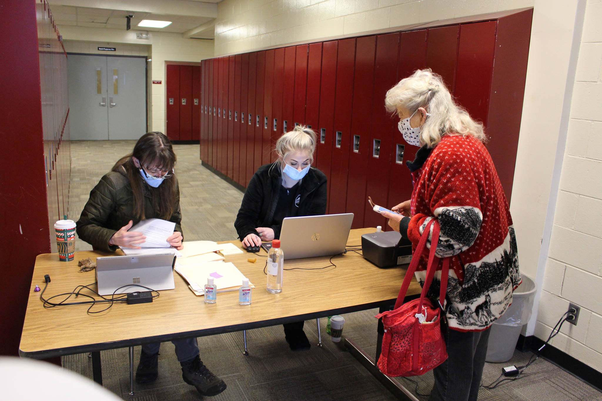 Julie Denison, member of the Kenai Peninsula Borough’s Incident Management Team, and Beth Wilson, pharmacy technician at Soldotna Professional Pharmacy, sign in Kenai Peninsula resident Lee Sparlin for her COVID-19 vaccine appointment at the Soldotna Prep School in Soldotna, Alaska on Jan. 23, 2021. (Photo by Brian Mazurek/Peninsula Clarion)