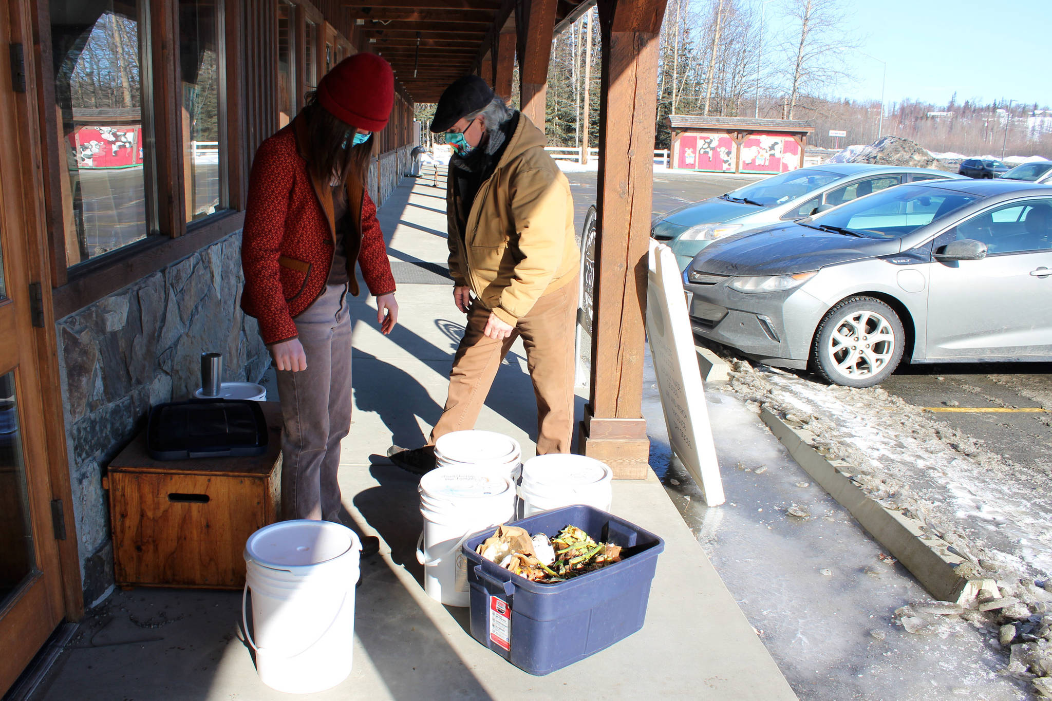 Kaitlin Vadla (left) and Timm Johnson prepare buckets of compost on Thursday, April 1, 2021, in Soldotna, Alaska. (Ashlyn O’Hara/Peninsula Clarion)