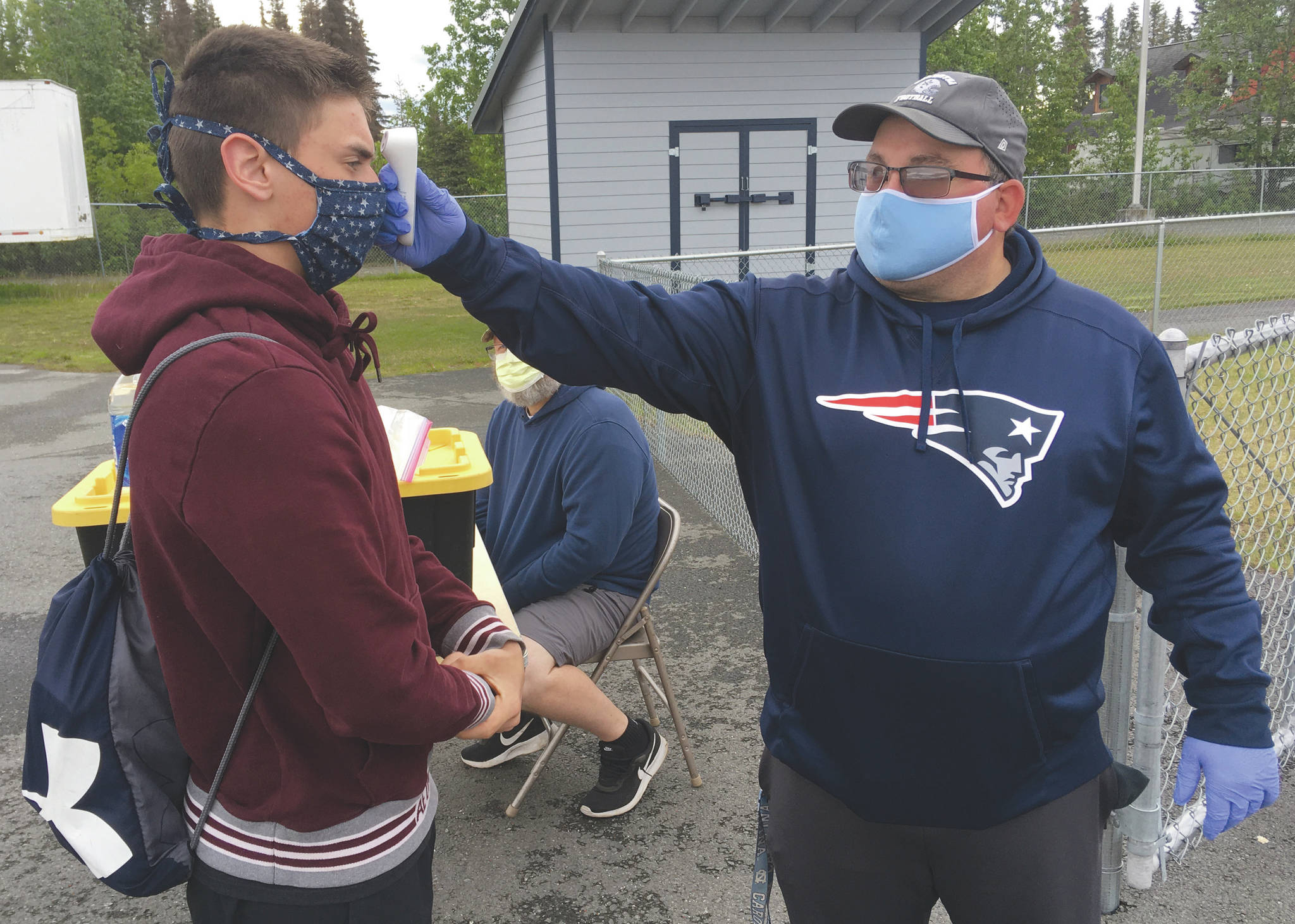 Soldotna assistant football coach Eric Pomerleau checks the temperature of sophomore Joseph Whittom before summer workouts Wednesday, June 17, 2020, at Soldotna High School in Soldotna, Alaska. (Photo by Jeff Helminiak/Peninsula Clarion)