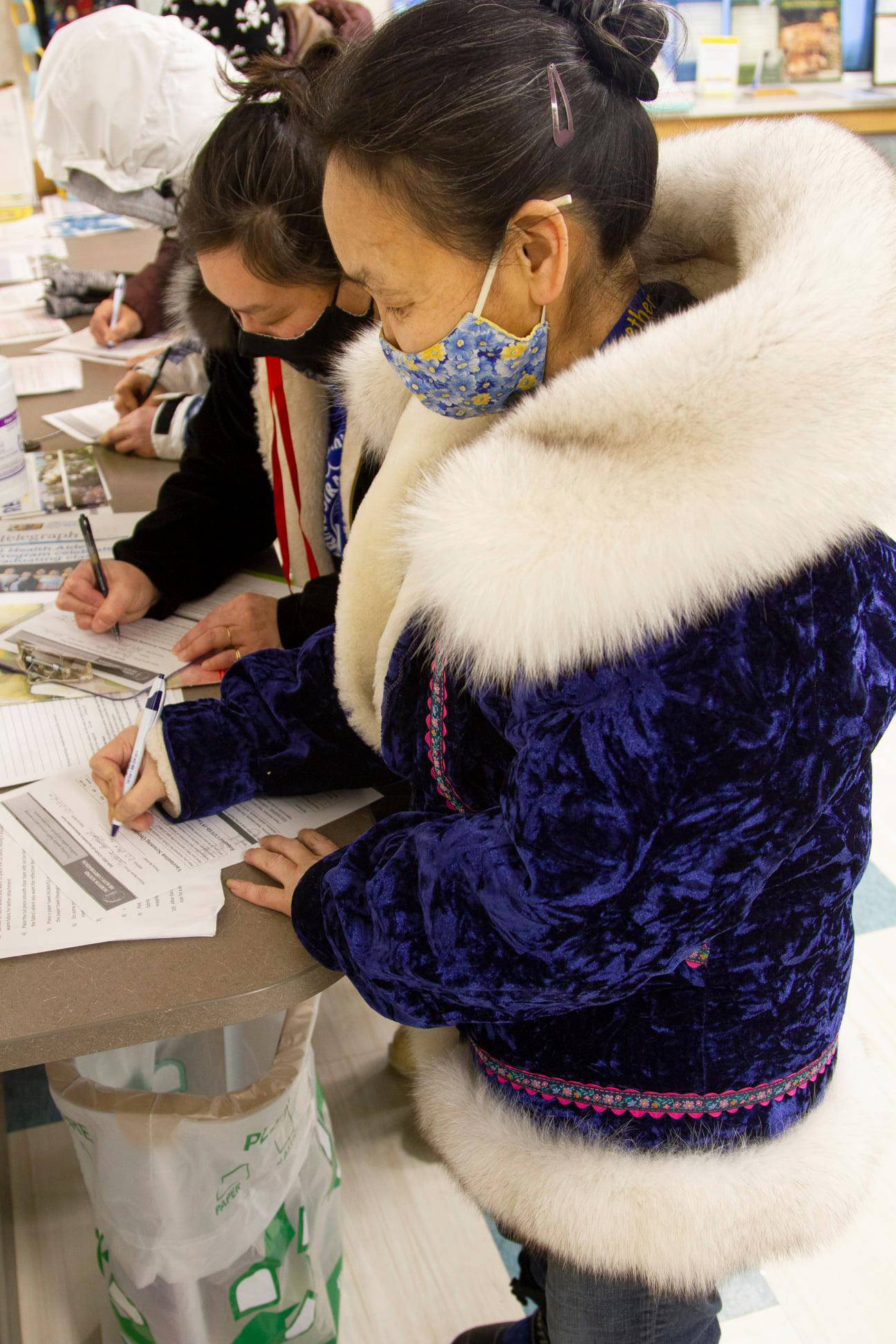 In this photo, provided by Norton Sound Health Corp., are Joey Annogiyuk, left, and Miriam Toolie signing up to receive the Pfizer vaccine at the Savoonga Clinic in Savoonga, Alaska, on Jan. 14, 2021. Some of Alaska’s highest vaccination rates among those 16 or older have been in some of its remotest, hardest-to-access communities, where the toll of past flu or tuberculosis outbreaks hasn’t been forgotten. (Reba Lean/Norton Sound Health Corp. via AP)