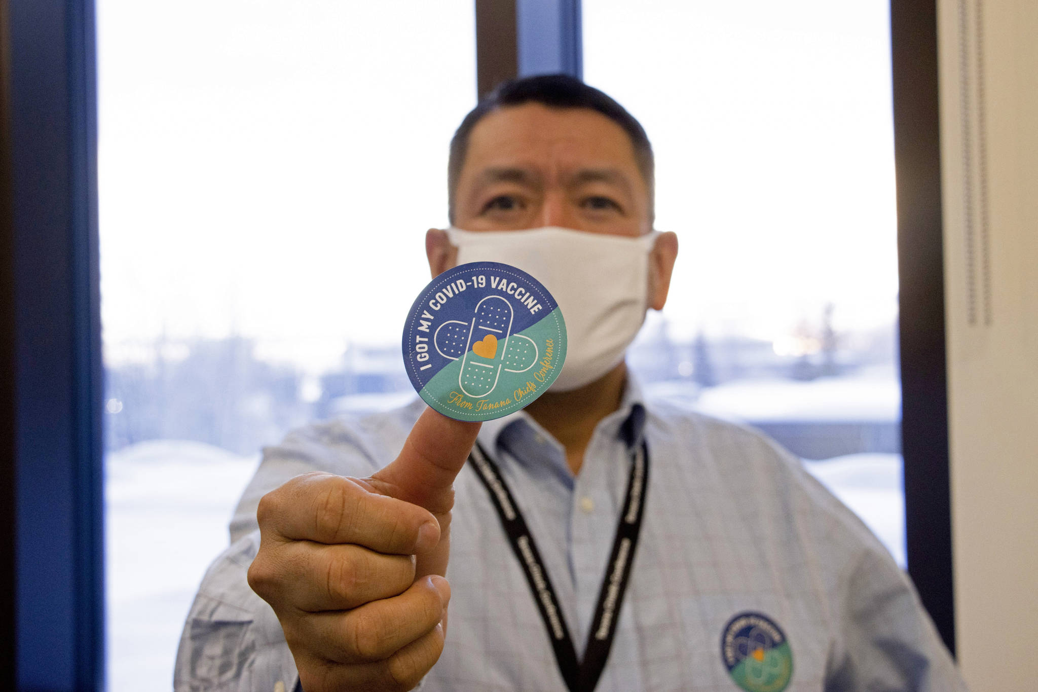 In this undated photo provided by the Tanana Chiefs Conference, shows PJ Simon, chief and chairman of the conference, from Fairbanks, Alaska, displaying a COVID-19 vaccination sticker. Alaska has been one of the leading states in the percentage of its population to be vaccinated against COVID-19. But some of Alaska’s highest vaccination rates have been in some of its most remote, hardest-to-access communities, where the toll of past flu or tuberculosis outbreaks hasn’t been forgotten. (Rachel Saylor/Tanana Chiefs Conference via AP)