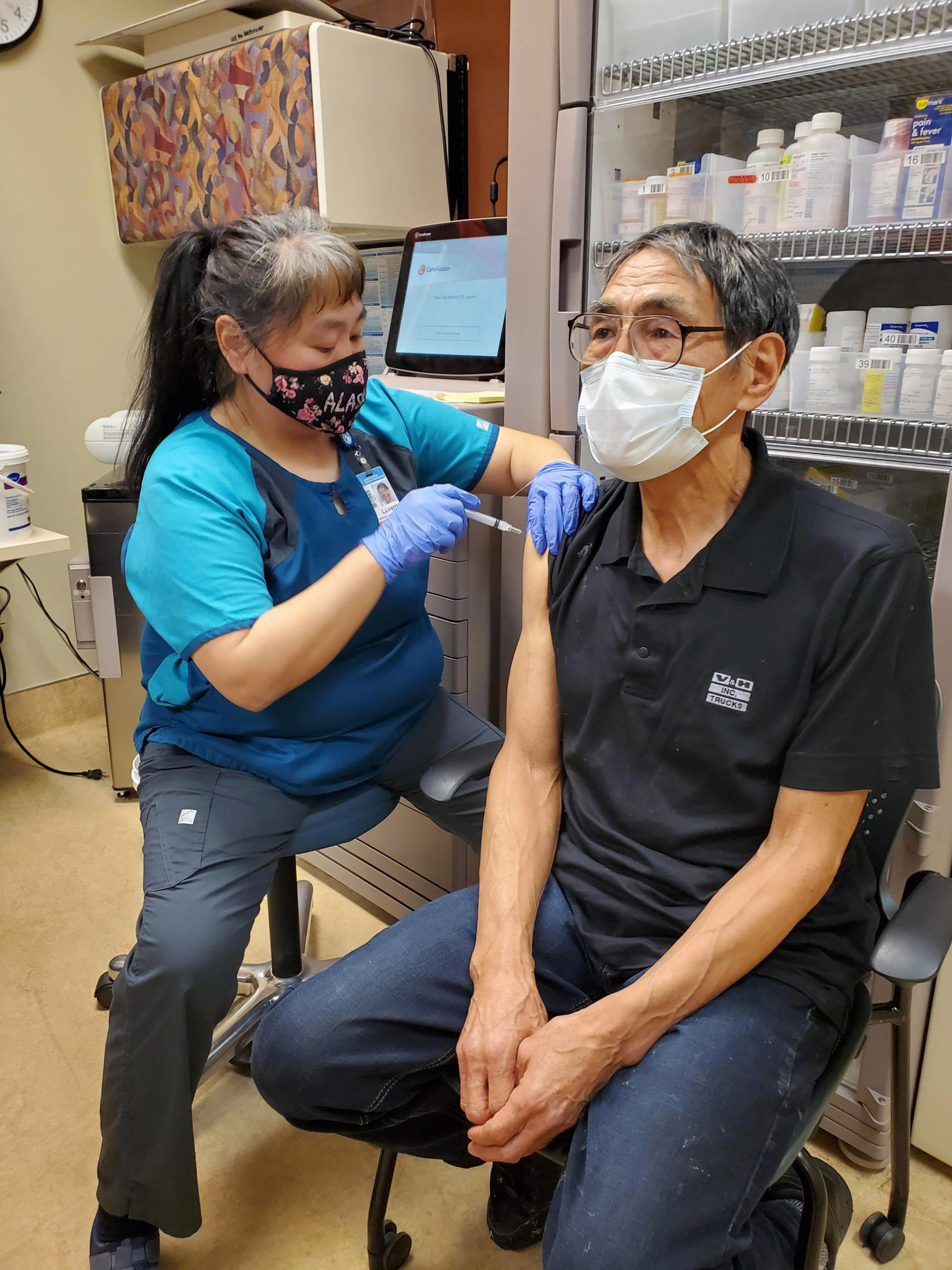 In this photo provided by Norton Sound Health Corp., is nurse LaVerne Saccheus providing a vaccination to Unalakleet elder Joseph “Nupid” Katchatag in Unalakleet, Alaska, on Dec. 23, 2020. Alaska’s highest vaccination rates among those 16 or older have been in some of its remotest, hardest-to-access communities, where the toll of past flu or tuberculosis outbreaks hasn’t been forgotten. (Carol Charles/Norton Sound Health Corp. via AP)