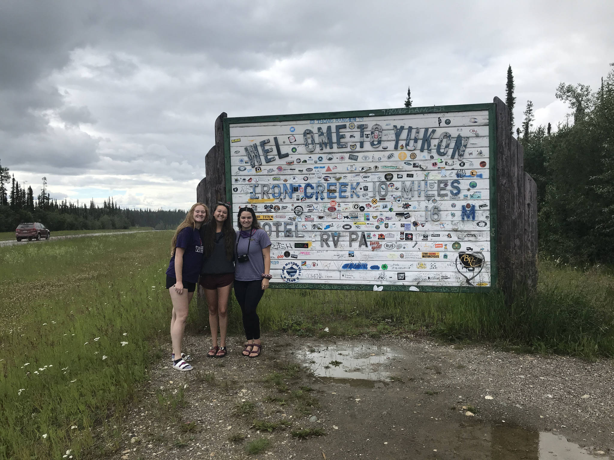 From left to right: Camille Botello, Emma Schoonover and Grace Thompson-Johnston stand in front of a sign welcoming them to the Yukon territory in Canada as they make their way up the Alaska Highway on July 16, 2020. (Photo provided)