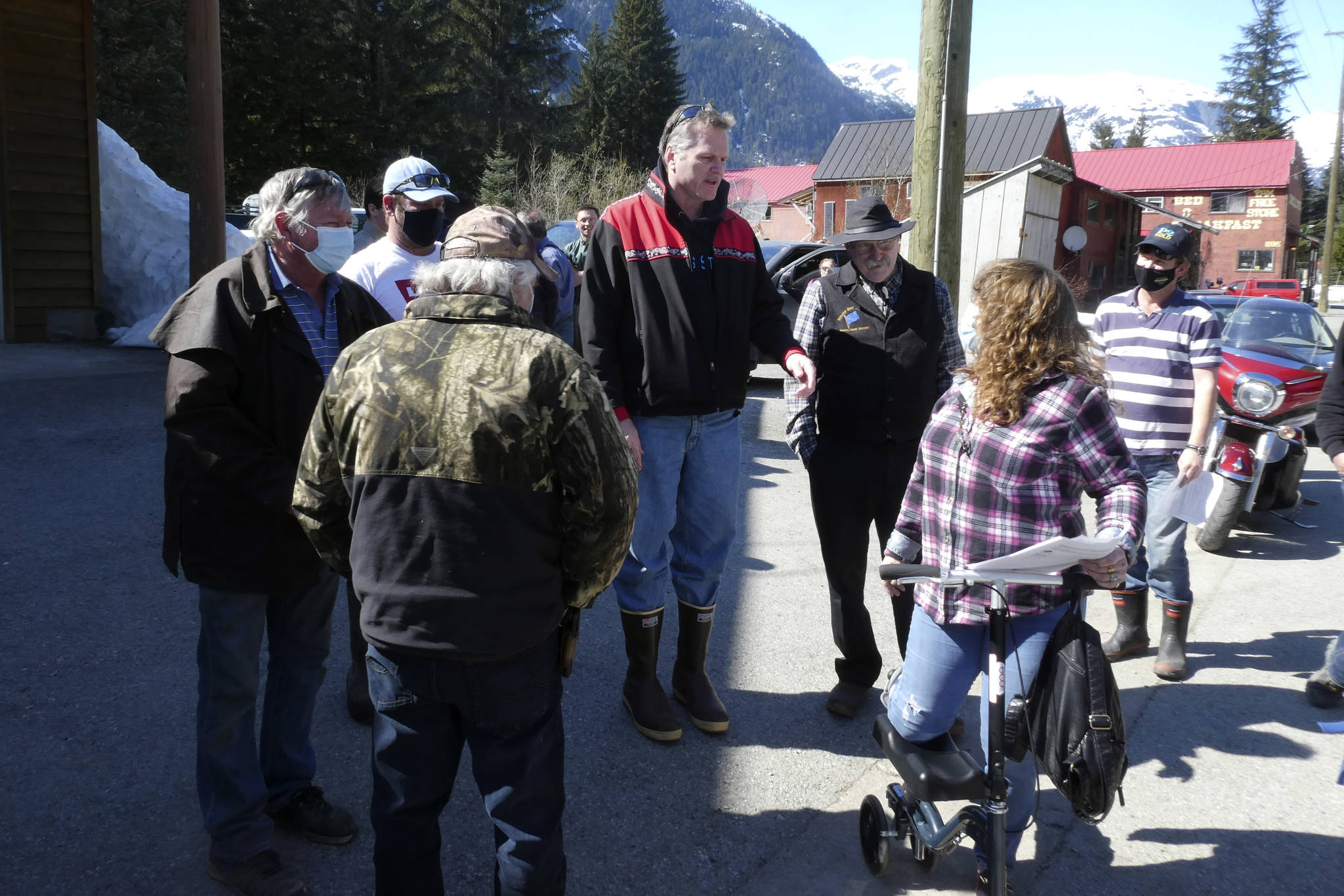 Alaska Gov. Mike Dunleavy, center, meets with people near an outdoor COVID-19 vaccination clinic in Hyder, Alaska, on Thursday, April 22, 2021. Dunleavy said Alaska is in a fortunate position with its vaccine supply and he wants to share vaccines with people across the border in Stewart, British Columbia, a community that has close ties to Hyder. (AP Photo/Becky Bohrer)