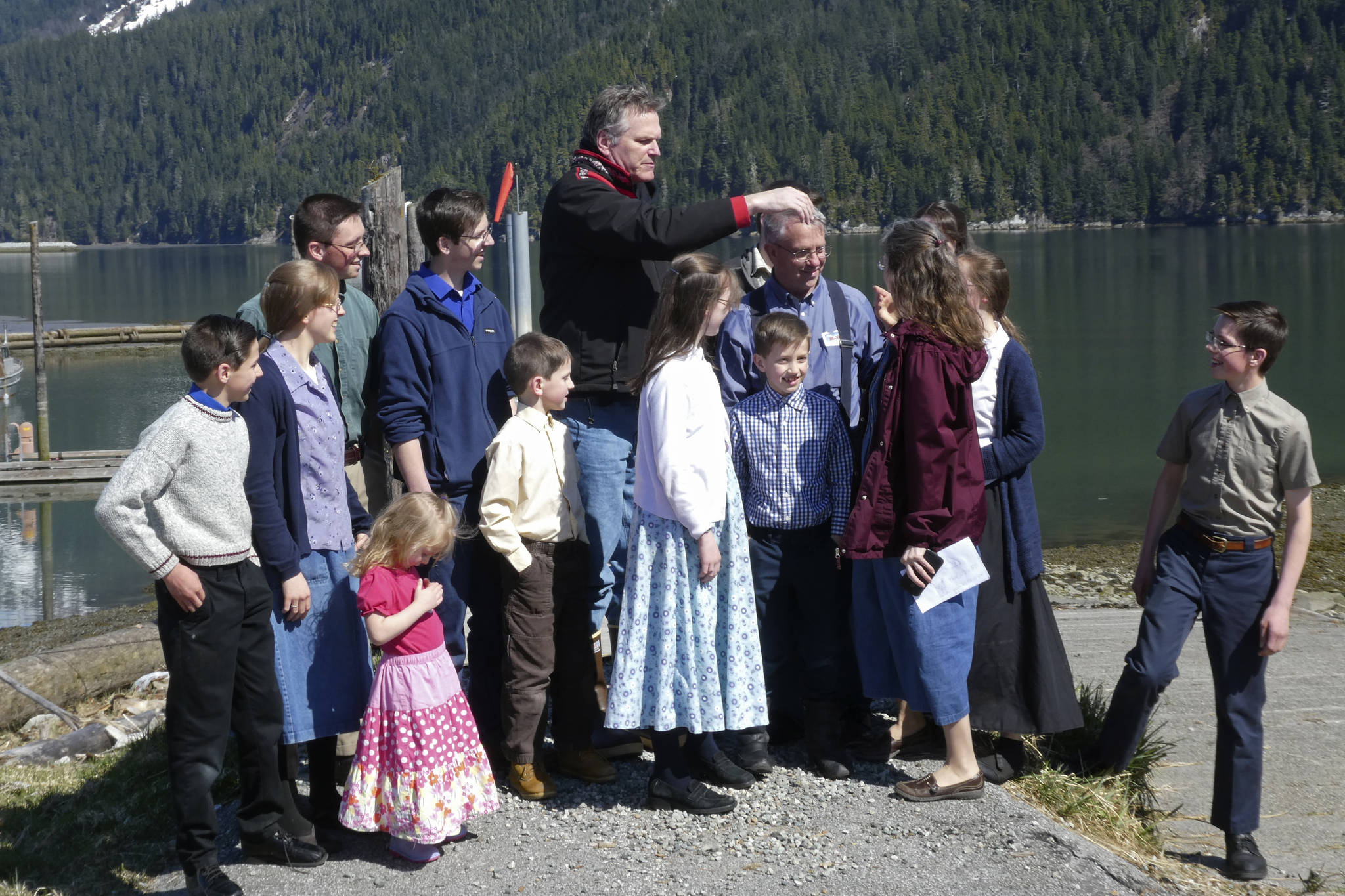 Alaska Gov. Mike Dunleavy, center, gathers with members of Mark and Amy Bach’s family as they prepare to pose for a photo on Thursday, April 22, 2021, in Hyder, Alaska. The family also invited Dunleavy to their home before he left Hyder, a small community near the U.S.-Canada border and one of the stops on Dunleavy’s one-day visit to southeast Alaska communities on April 22, 2021. (AP Photo/Becky Bohrer)