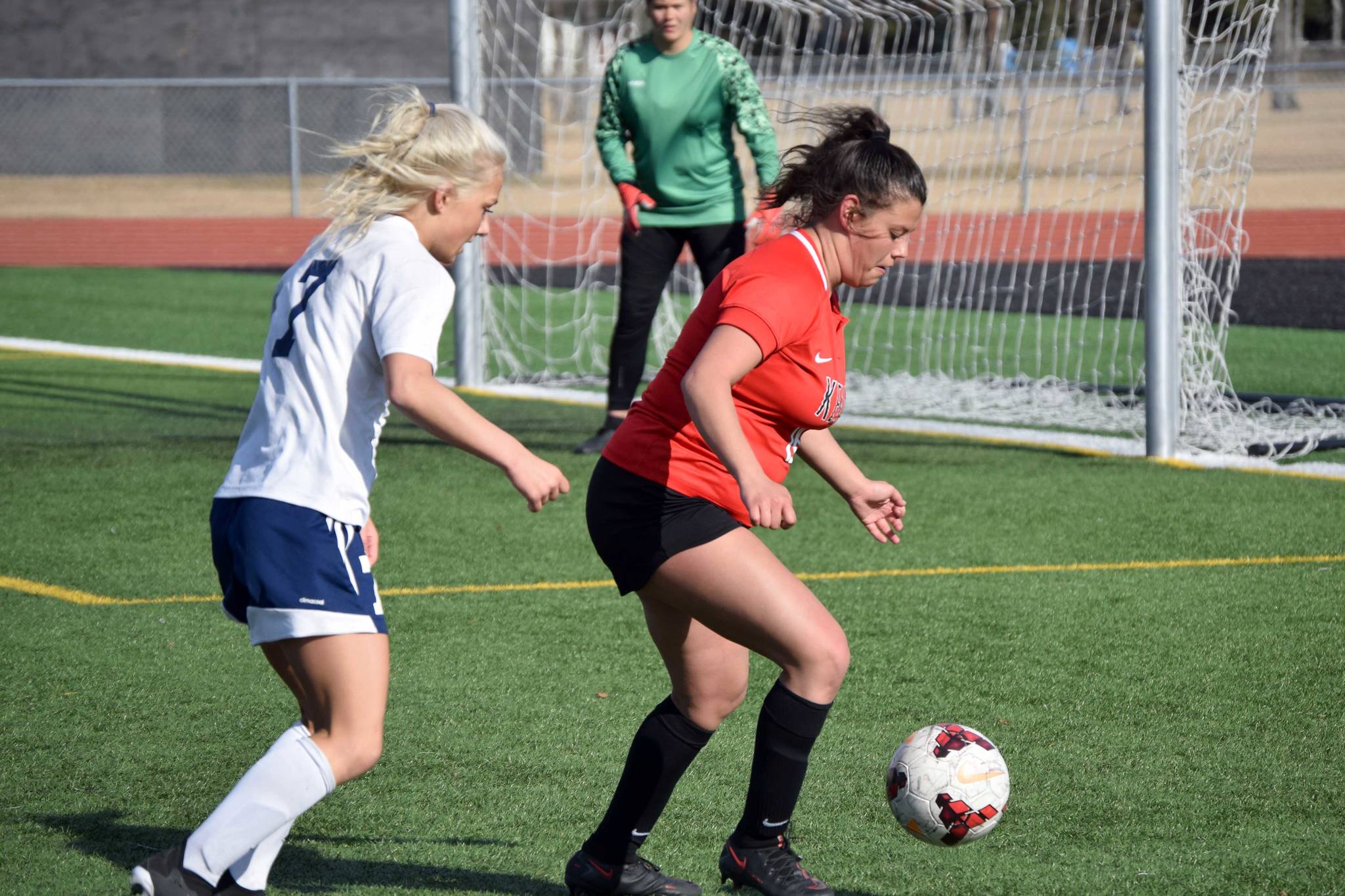 Kenai Central defender Valerie Villegas keeps the ball from Homer's Sela Weisser in front of Kenai goalie Emma Beck on Thursday, May 6, 2021, at Kenai Central High School in Kenai, Alaska. (Photo by Jeff Helminiak/Peninsula Clarion)