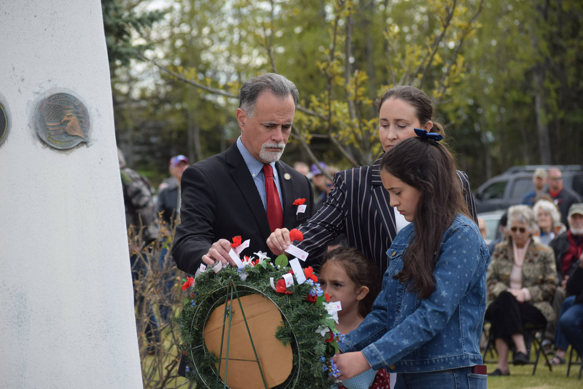 Alaska Senate President Peter Micciche (R-Soldotna) lays a poppy flower on a remberance wreath with his family during the Memorial Day ceremony at Leif Hansen Memorial Park in Kenai, Alaska, on Monday, May 31, 2021. (Camille Botello/Peninsula Clarion)