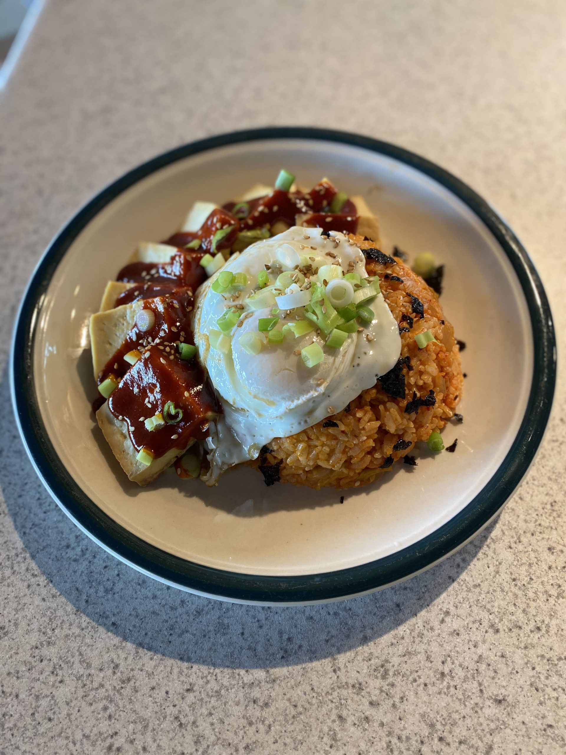 A fried egg, crushed seaweed paper, green onions and sesame seeds top this classic Korean kimchi dish. (Photo by Tress Dale/Peninsula Clarion)