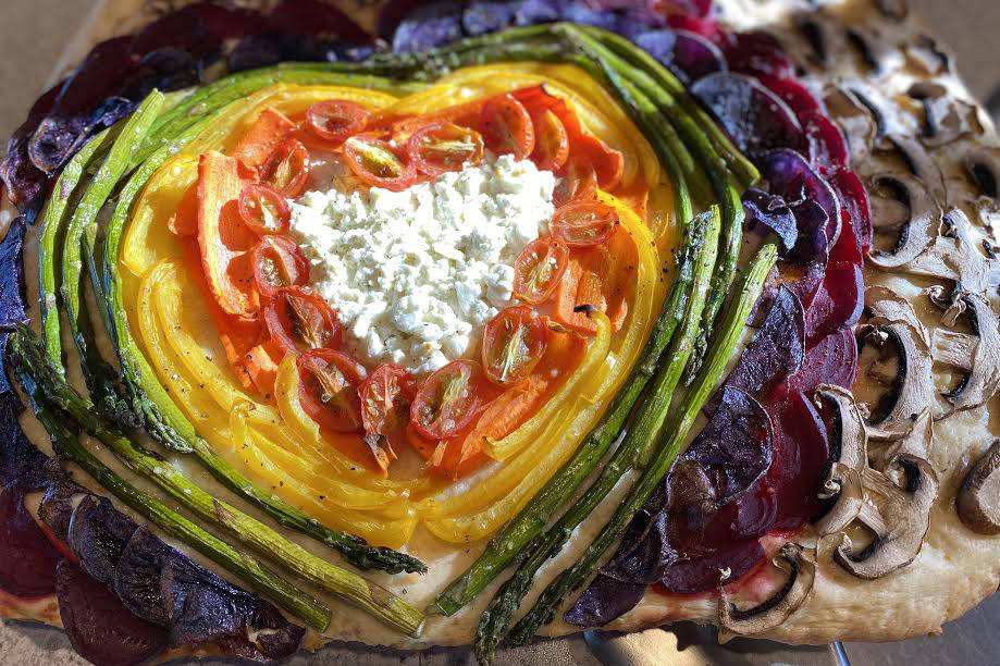 Tressa Dale / Peninsula Clarion
Feta and Parmesan cheese, cherry tomatoes, carrot, yellow bell pepper, asparagus, purple potatoes, beets and white button mushrooms form into a rainbow with a cheesy heart on focaccia bread.