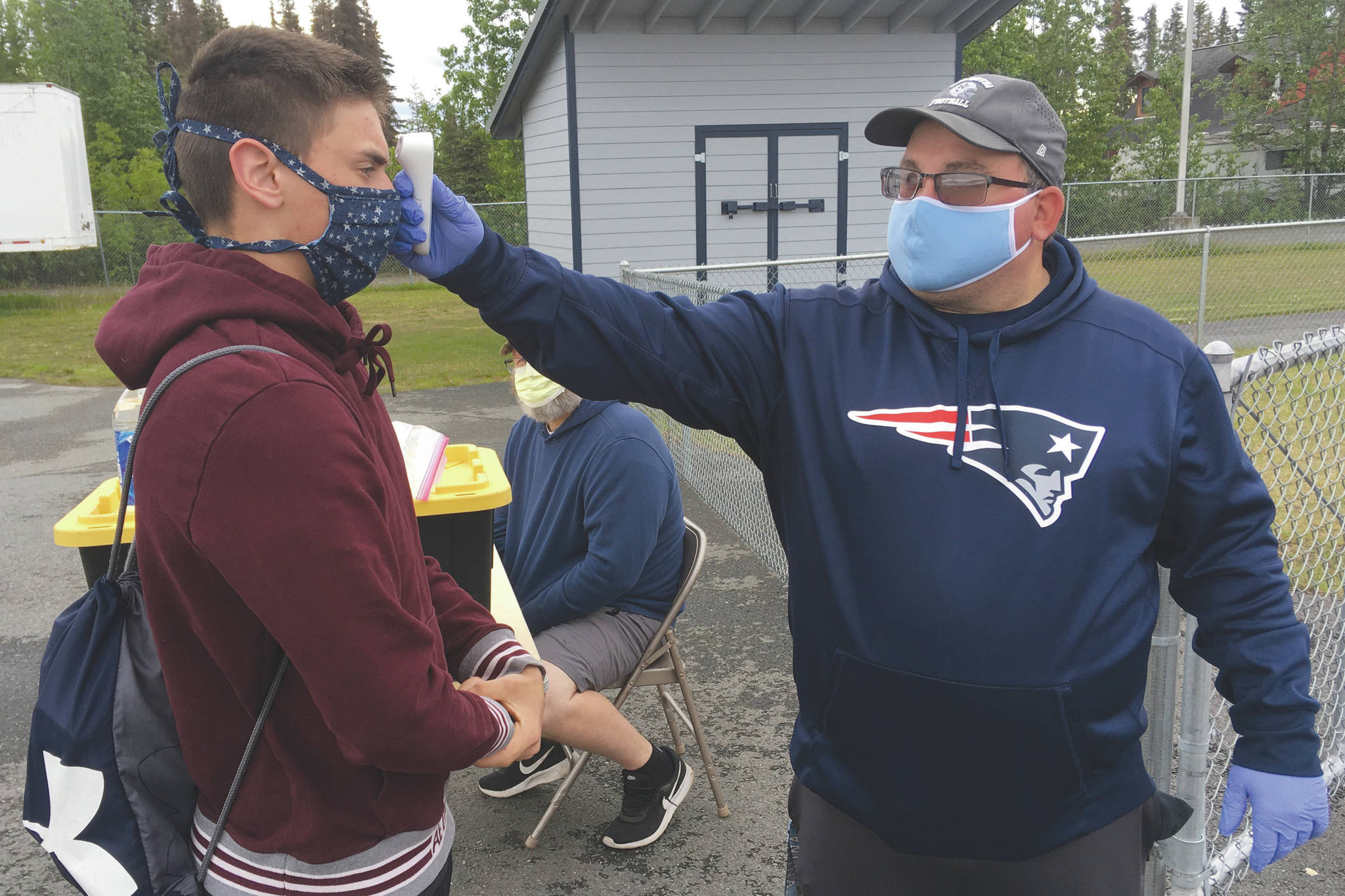 Soldotna assistant football coach Eric Pomerleau checks the temperature of sophomore Joseph Whittom before summer workouts Wednesday, June 17, 2020, at Soldotna High School in Soldotna, Alaska. (Photo by Jeff Helminiak/Peninsula Clarion)
