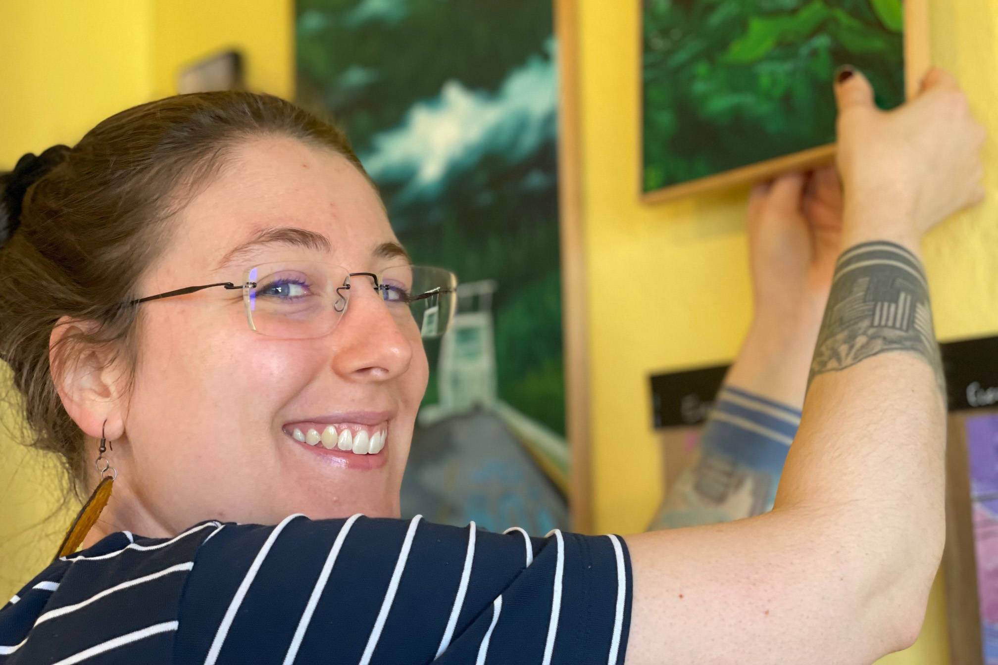 Homer artist Jenna Gerrety straightens paintings currently being shown at Sustainable Wares. (Photo by McKibben Jackinsky)
