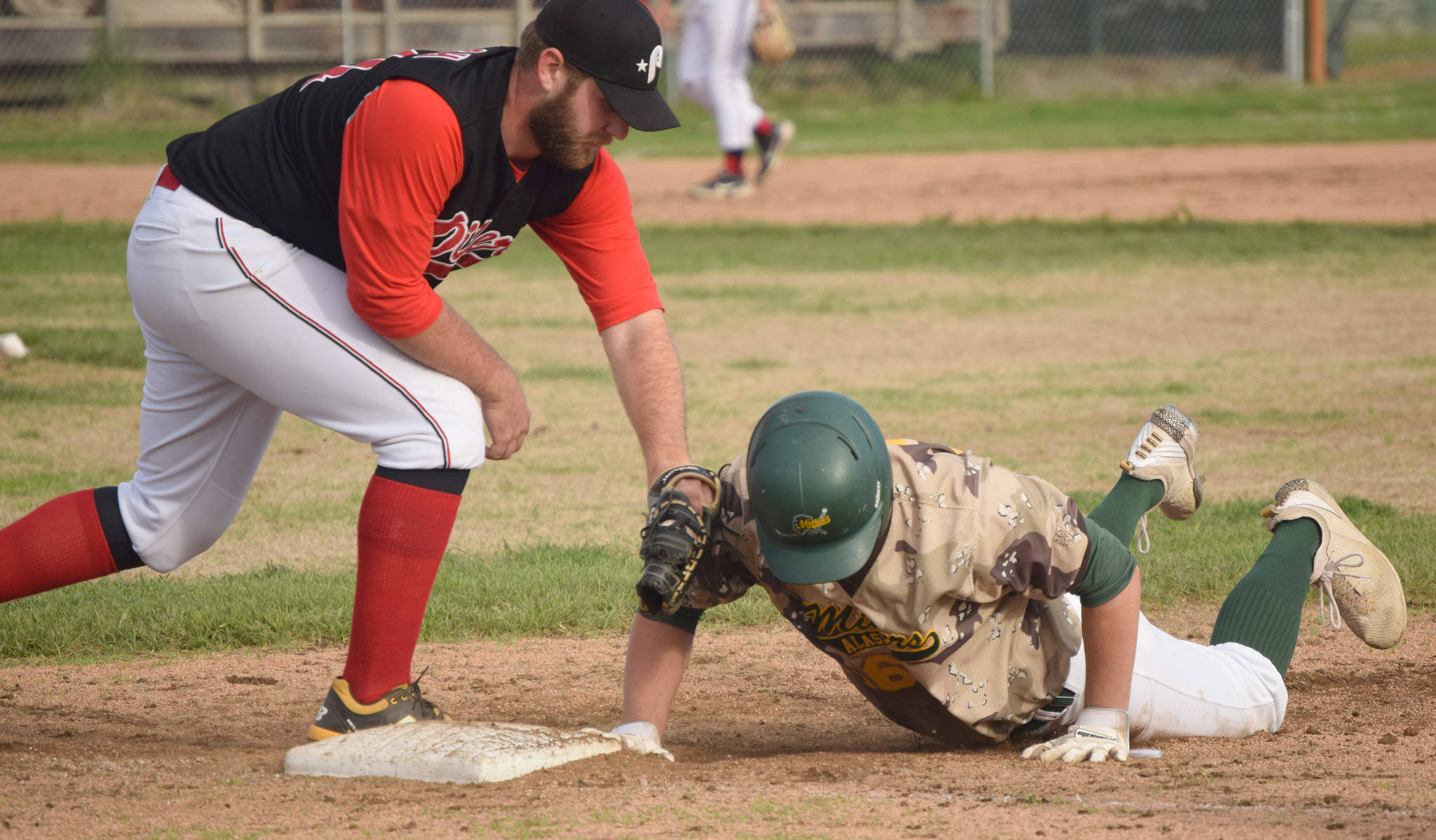 Mike Ferrara of the Mat-Su Miners dives safely back to first base in front of Oilers first baseman Bryce Marsh on Monday, June 21, 2021, at Coral Seymour Memorial Park in Kenai, Alaska. (Photo by Jeff Helminiak/Peninsula Clarion)