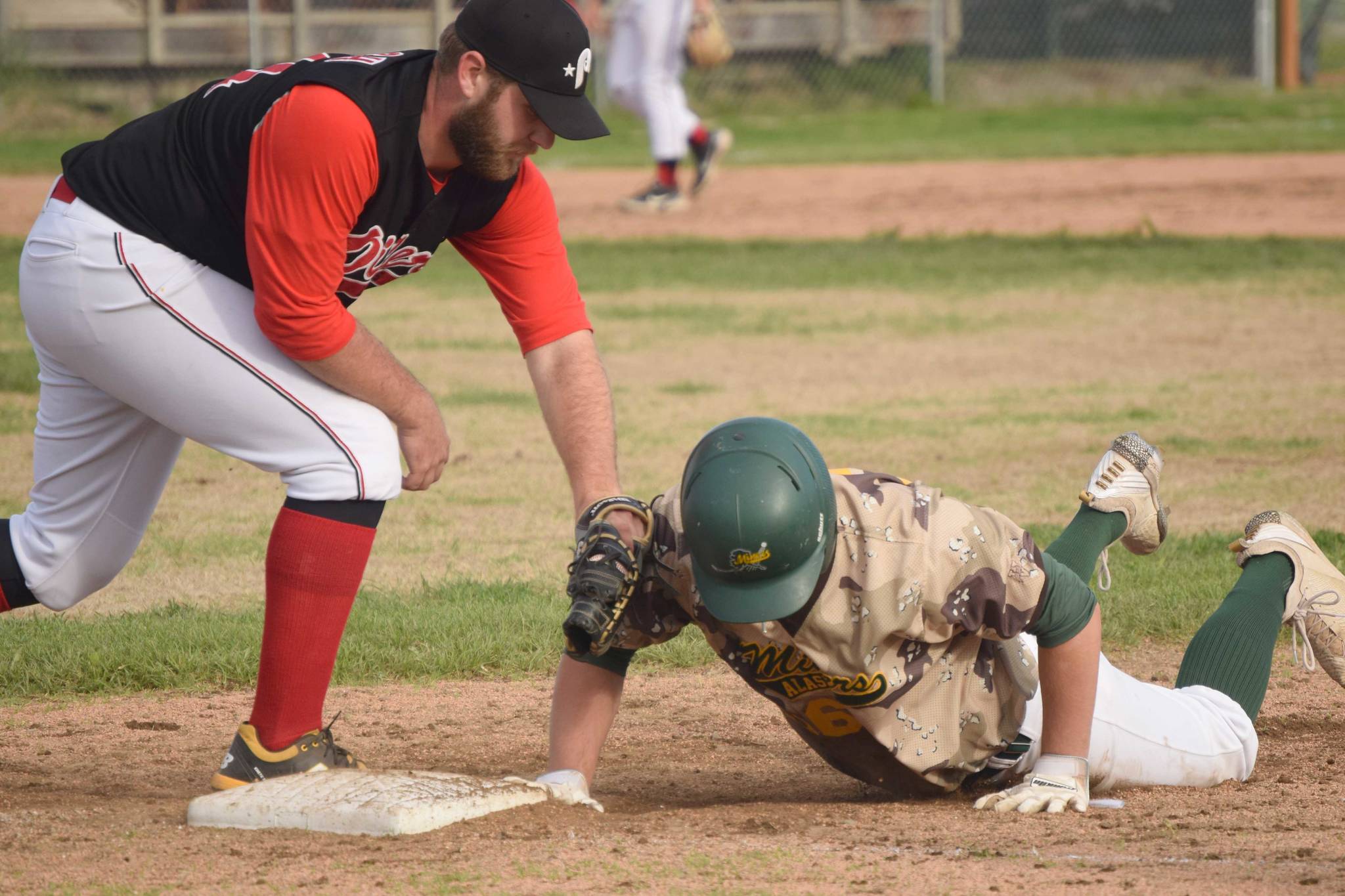 Mike Ferrara of the Mat-Su Miners dives safely back to first base in front of Oilers first baseman Bryce Marsh on Monday, June 21, 2021, at Coral Seymour Memorial Park in Kenai, Alaska. (Photo by Jeff Helminiak/Peninsula Clarion)