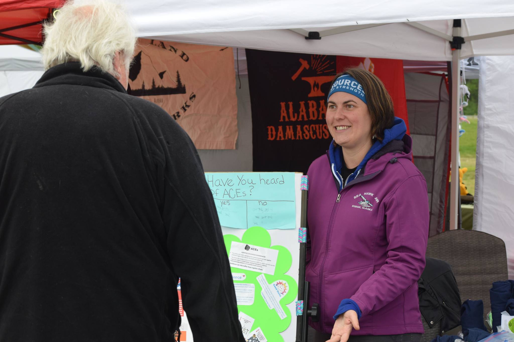 Emily Alvey explains the importance of trauma and adverse childhood experience awareness in her booth at the Soldotna Creek Park Wednesday Market on June 23, 2021. (Camille Botello/Peninsula Clarion)