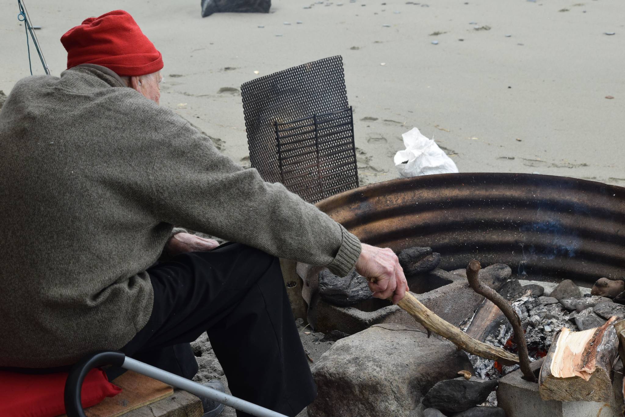 Ventis Plume tends to his fire at the end of his 10-day setnet trip at the Kasilof River State Recreational Site in Kasilof, Alaska, on June 25, 2021. (Camille Botello / Peninsula Clarion)