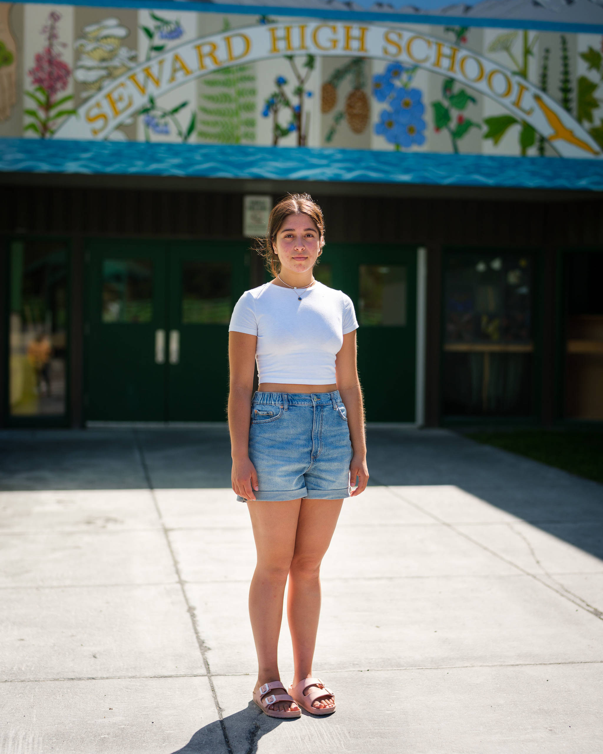 Selma Casagranda, a recent Seward High School graduate and lifelong resident of Seward, stands in front of her former school on May 25, 2021. (Young Kim for The Hechinger Report)