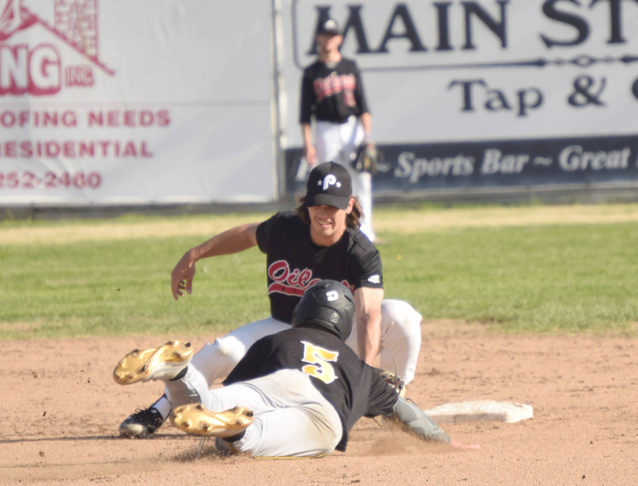 Peninsula Oilers shortstop Trevor Antonson tags out Garrett Ostrander of the Anchorage Bucs on a steal attempt Monday at Coral Seymour Memorial Park in Kenai. (Photo by Jeff Helminiak/Peninsula Clarion)