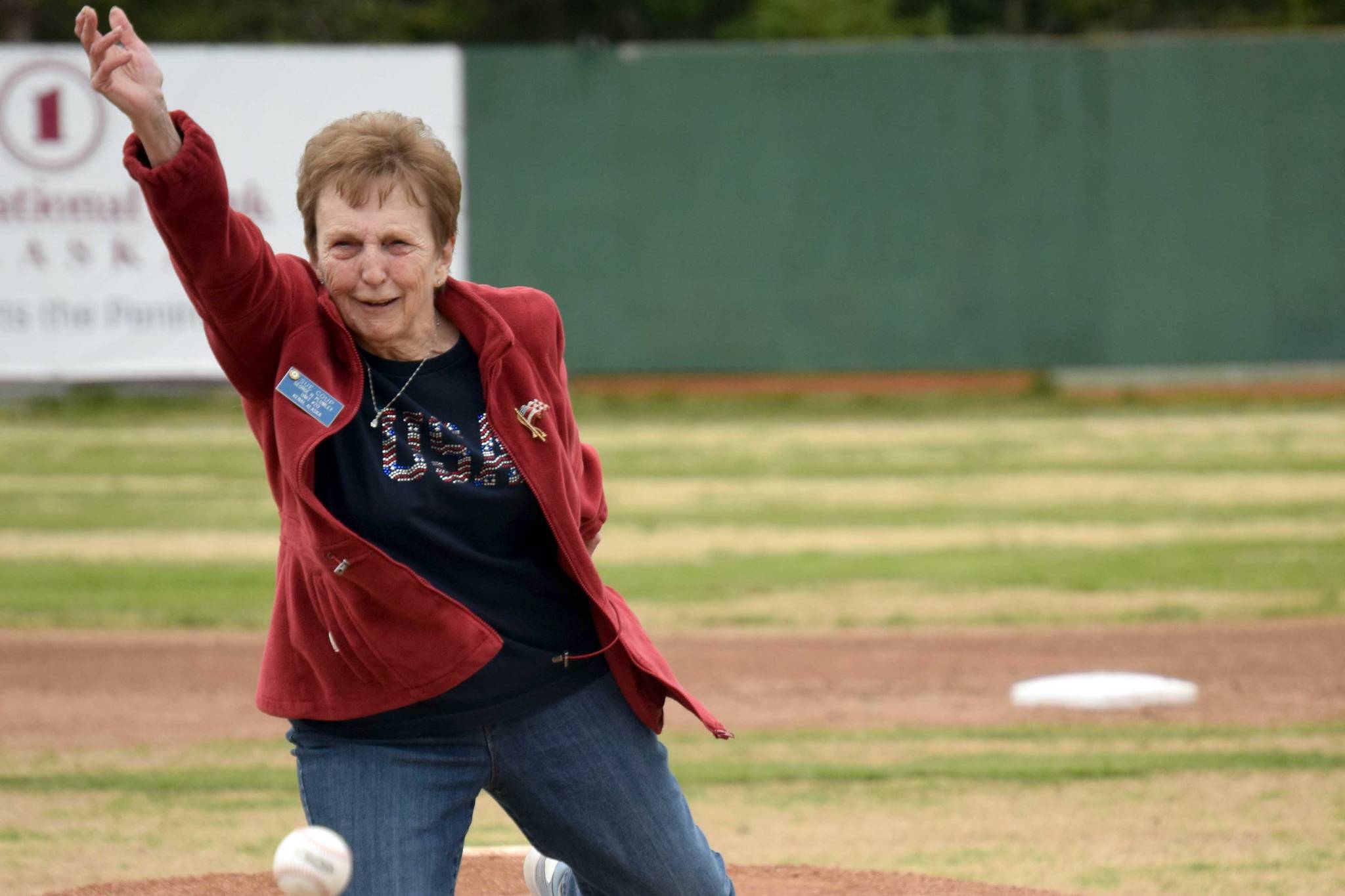 Nikiski's Sue Coup throws out the first pitch at a ceremony honoring former Twins head coach and general manager Lance Coz on Saturday, July 3, 2021, at Coral Seymour Memorial Park in Kenai, Alaska. (Photo by Jeff Helminiak/Peninsula Clarion)