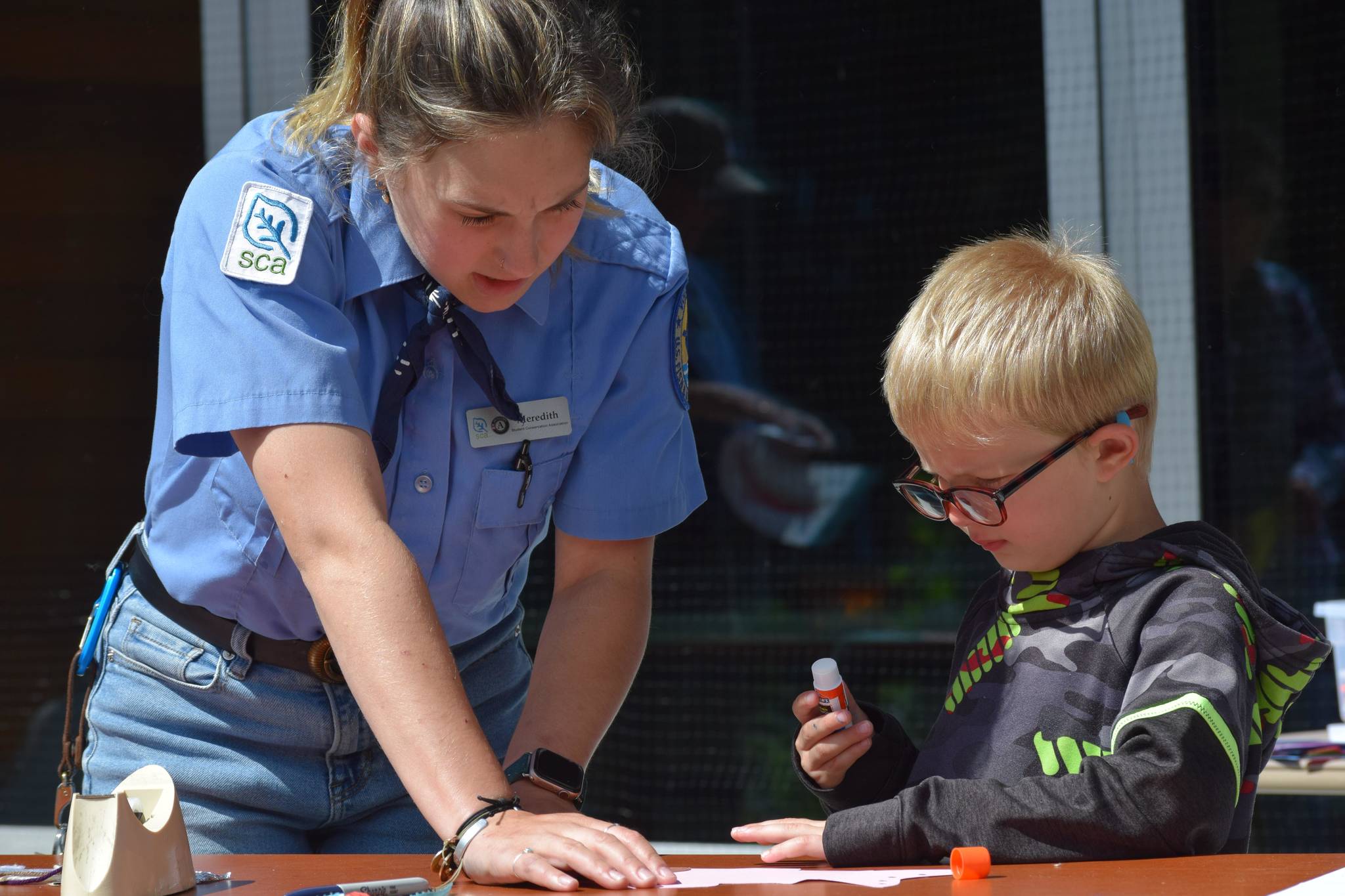 Ranger Meredith Baker helps Fredrick Bryant decorate a fish mobile at the Kenai Wildlife Refuge Visitor Center on July 6, 2021 for Fish Week. (Camille Botello / Peninsula Clarion)