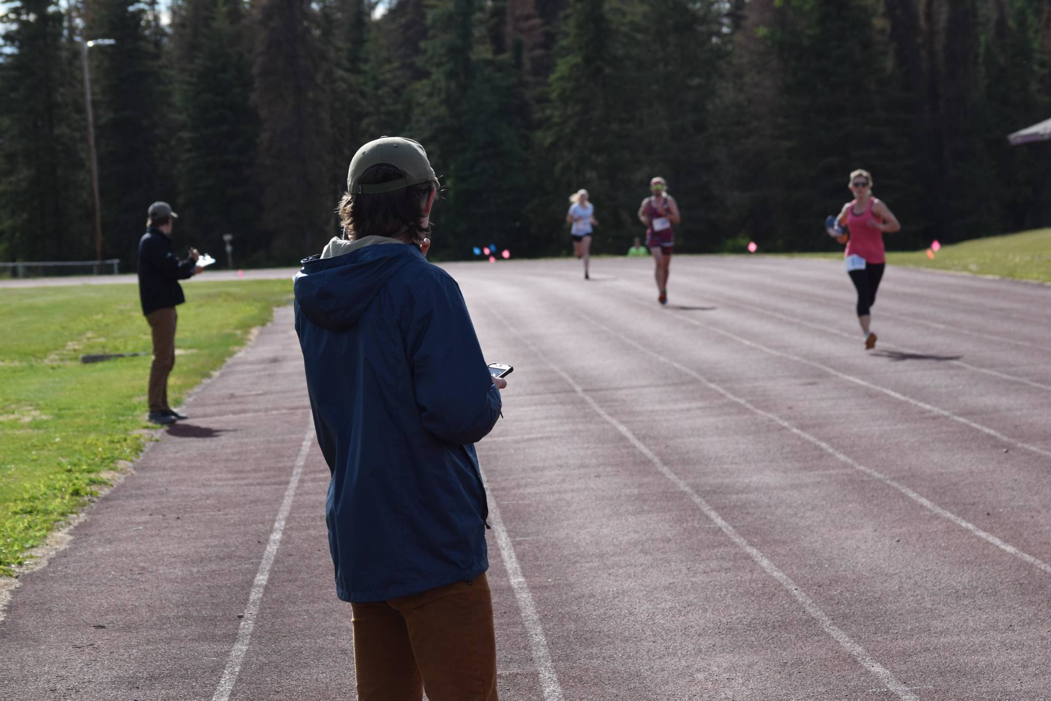 Kenai Watershed Forum Stream Watch Interns Brandom Drzazgowski and Jack Buban record 5K times of participants in the first race of the Salmon Run Series at the Skyview Middle School track on Wednesday, July 7, 2021. (Camille Botello / Peninsula Clarion)