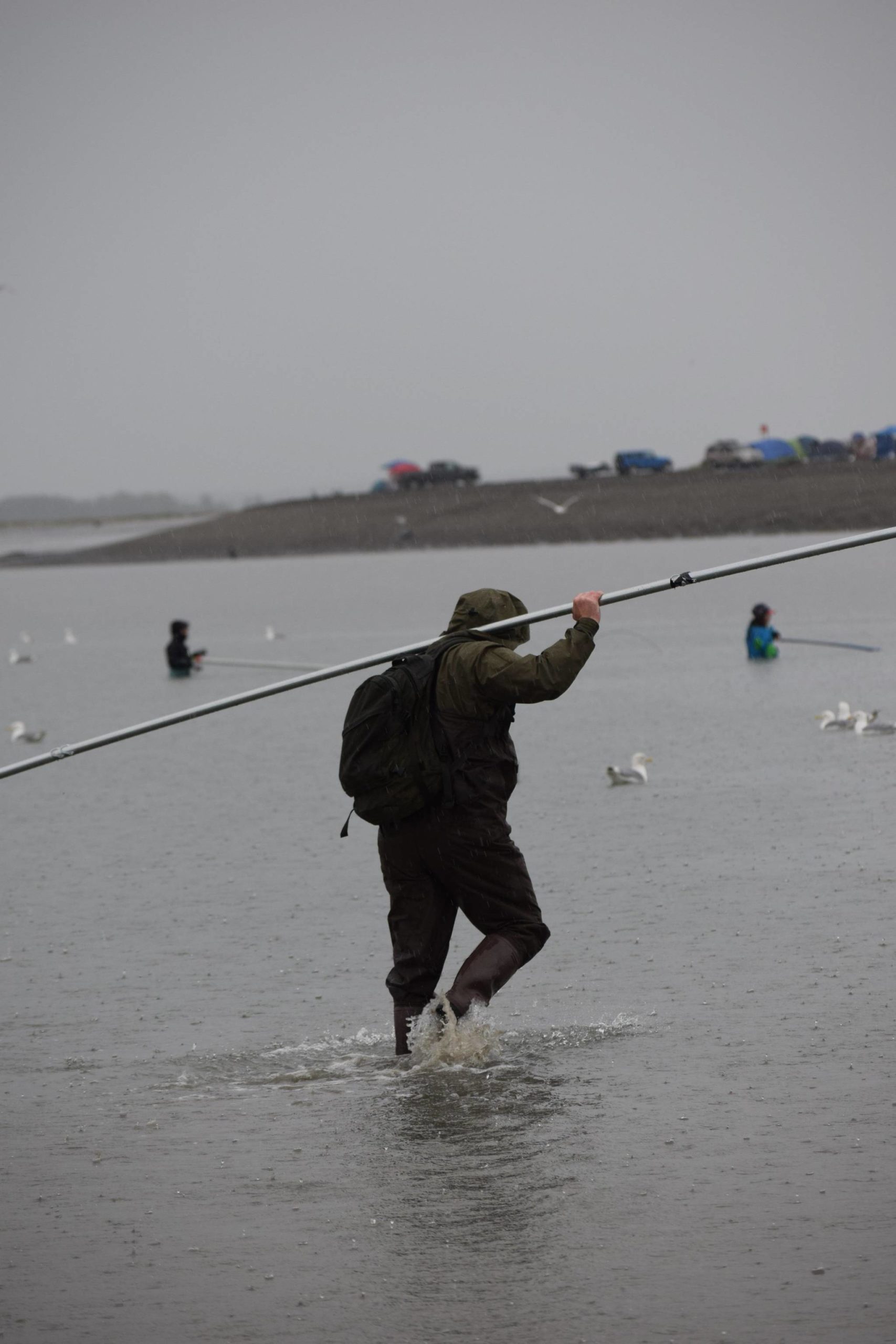 A fisher carries a net along North Kenai Beach on Saturday, July 10, 2021. (Camille Botello/Peninsula Clarion)