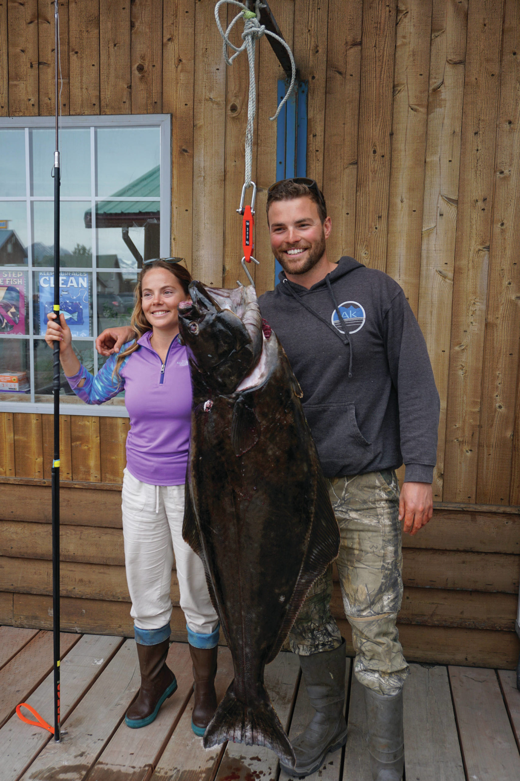 Lisa Stengel of Fort Lauderdale, Florida, poses for a photo with Capt. Brian Reid of the Castle Cape on Monday, July 12, 2021, at Coal Point Seafoods in Homer, Alaska, with a 71.4-pound halibut that she caught with a pole spear while free diving in Kachemak Bay. Stengel and her party went on a spearfishing expedition with Reid of Coldwater AK. (Photo by Michael Armstrong/Homer News)