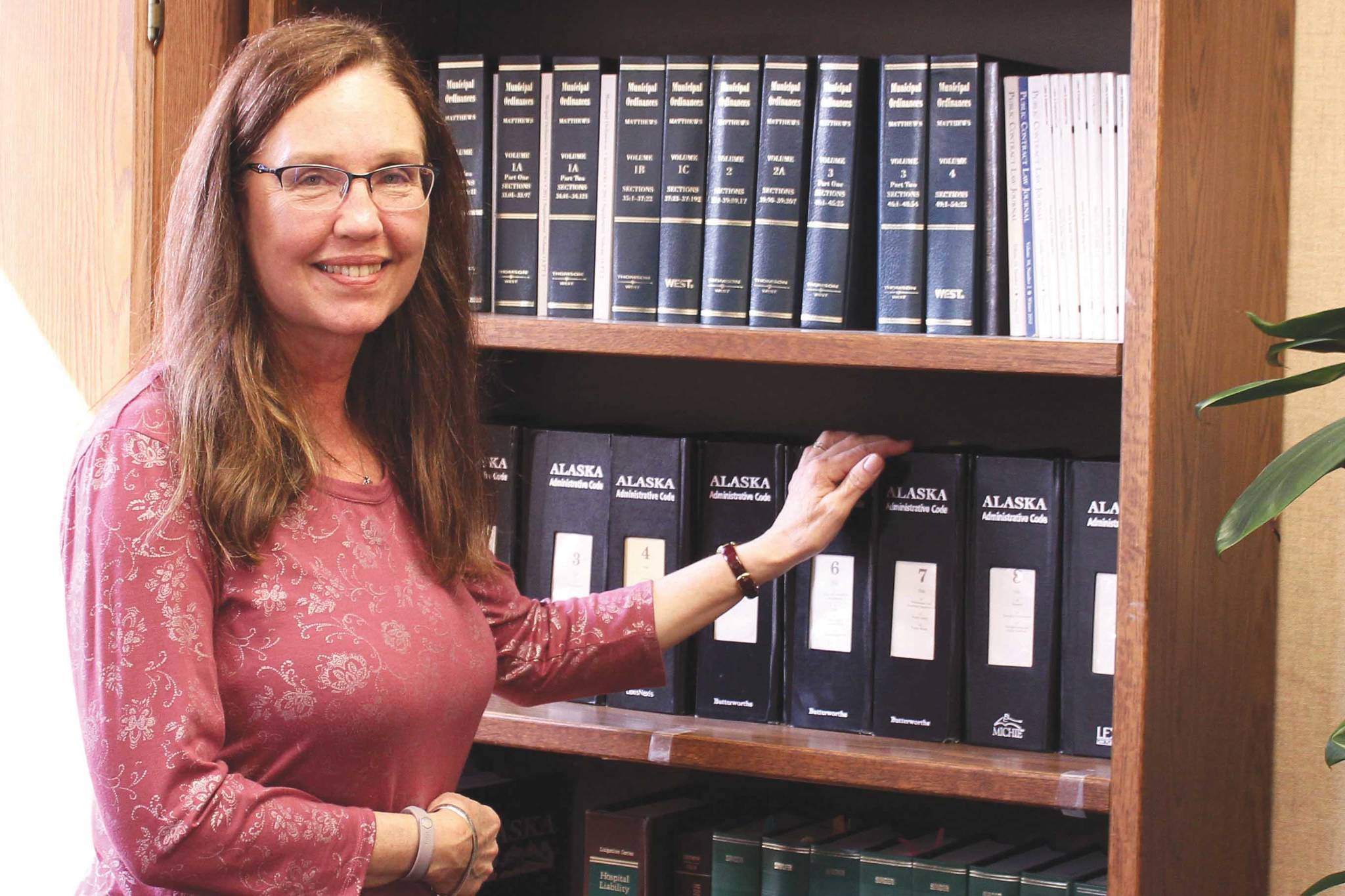 Colette Thompson stands near a bookshelf in her office at the George A. Navarre Borough Building on Thursday, July 15, 2021, in Soldotna, Alaska. (Ashlyn O'Hara/Peninsula Clarion)