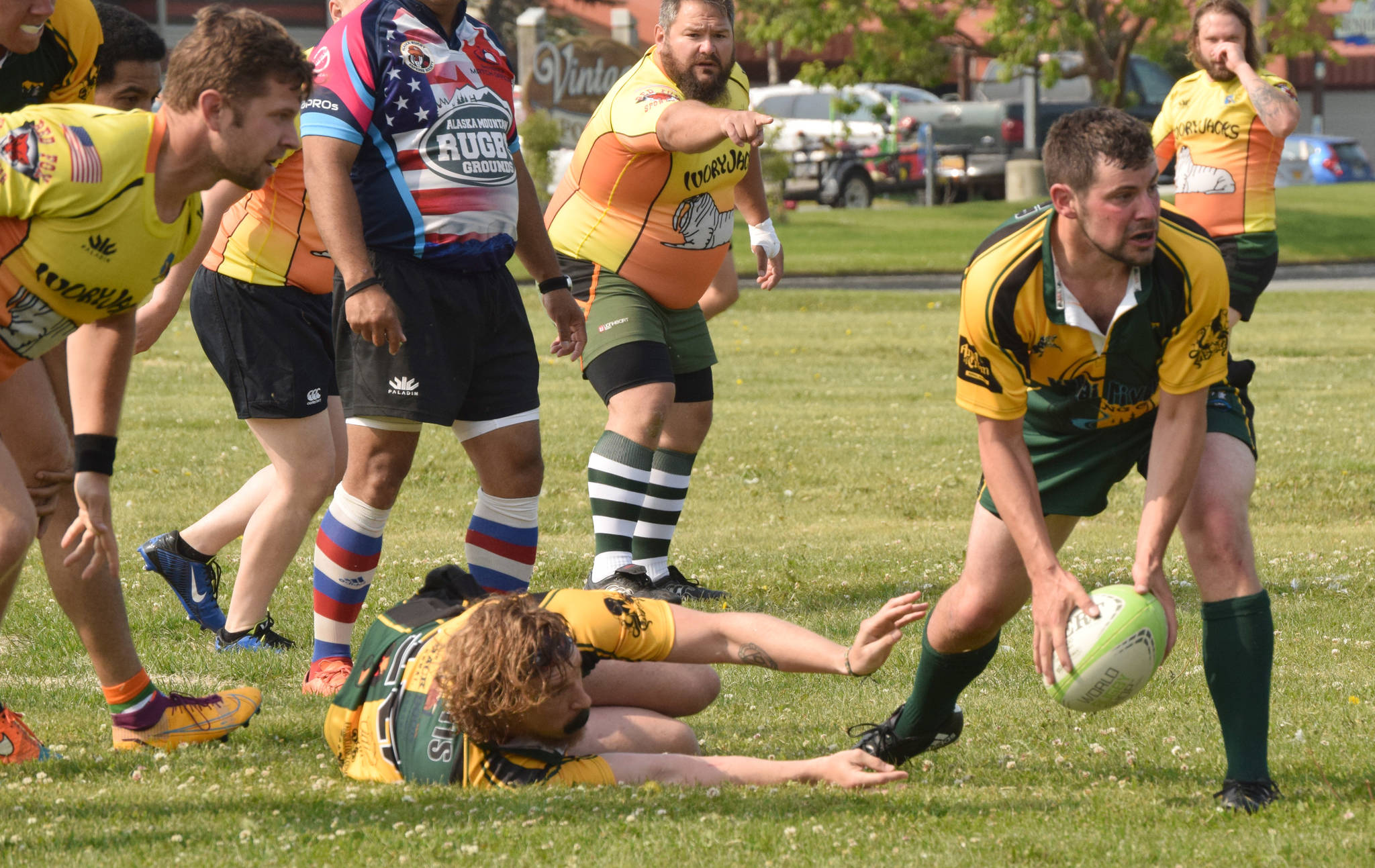 Kenai River Wolfpack scrum half Dan Balmer scoops up the ball left by tackled player Mike Curtis and passes it out to a receiving Wolfpack player while Fairbanks defenders Joshua Harold, Joe Prete and Sam Warner look on at Millennium Square in Kenai, Alaska, on Saturday, July 17, 2021, at the 2021 Kenai Dipnet Fest Rugby 10s Tournament.