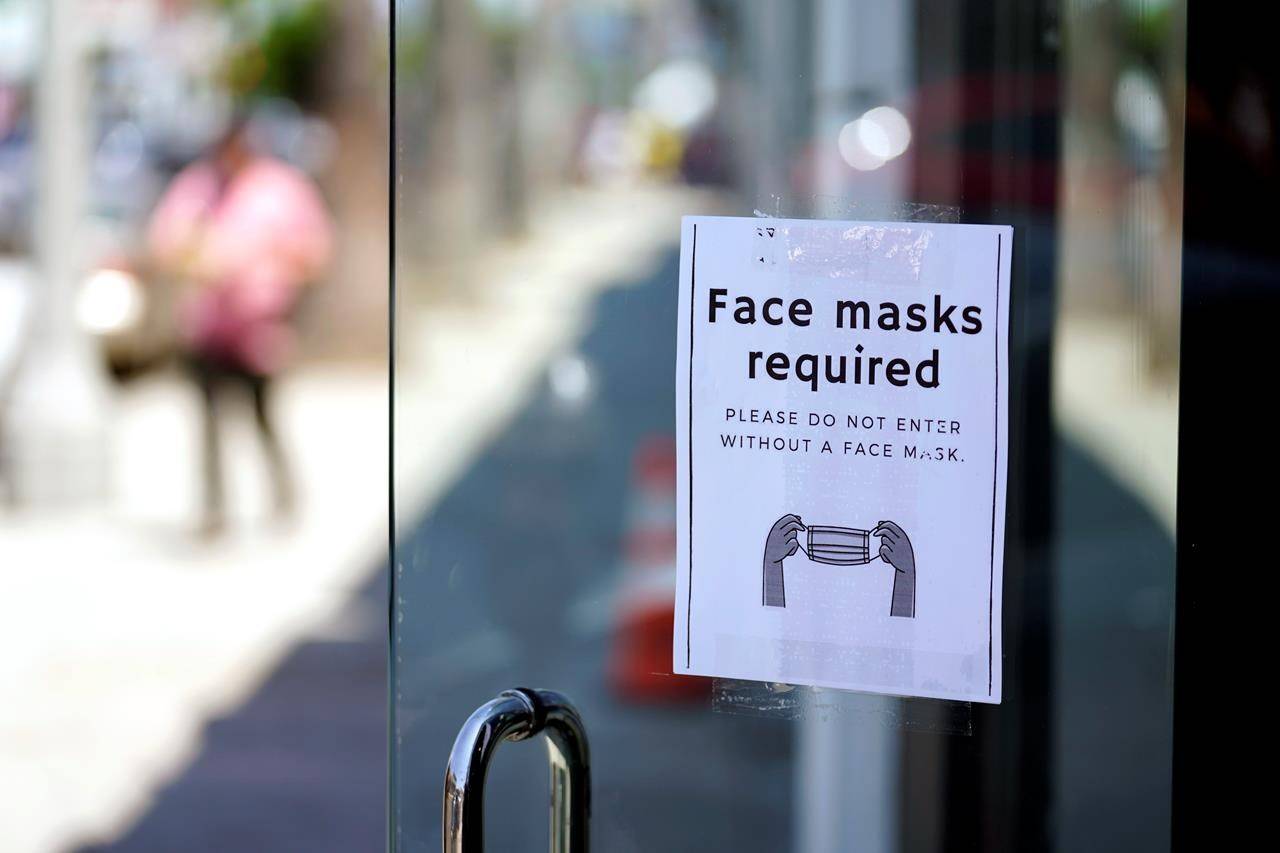 FILE - A sign advises shoppers to wear masks outside of a store Monday, July 19, 2021, in the Fairfax district of Los Angeles. Infections are climbing across the U.S. and mask mandates and other COVID-19 prevention measures are making a comeback in some places as health officials issue increasingly dire warnings about the highly contagious delta variant. But in a possible sign that the warnings are getting through to more Americans, vaccination rates are creeping up again, offering hope that the nation could yet break free of the coronavirus if people who have been reluctant to receive the shot are finally inoculated. (AP Photo/Marcio Jose Sanchez, File)
