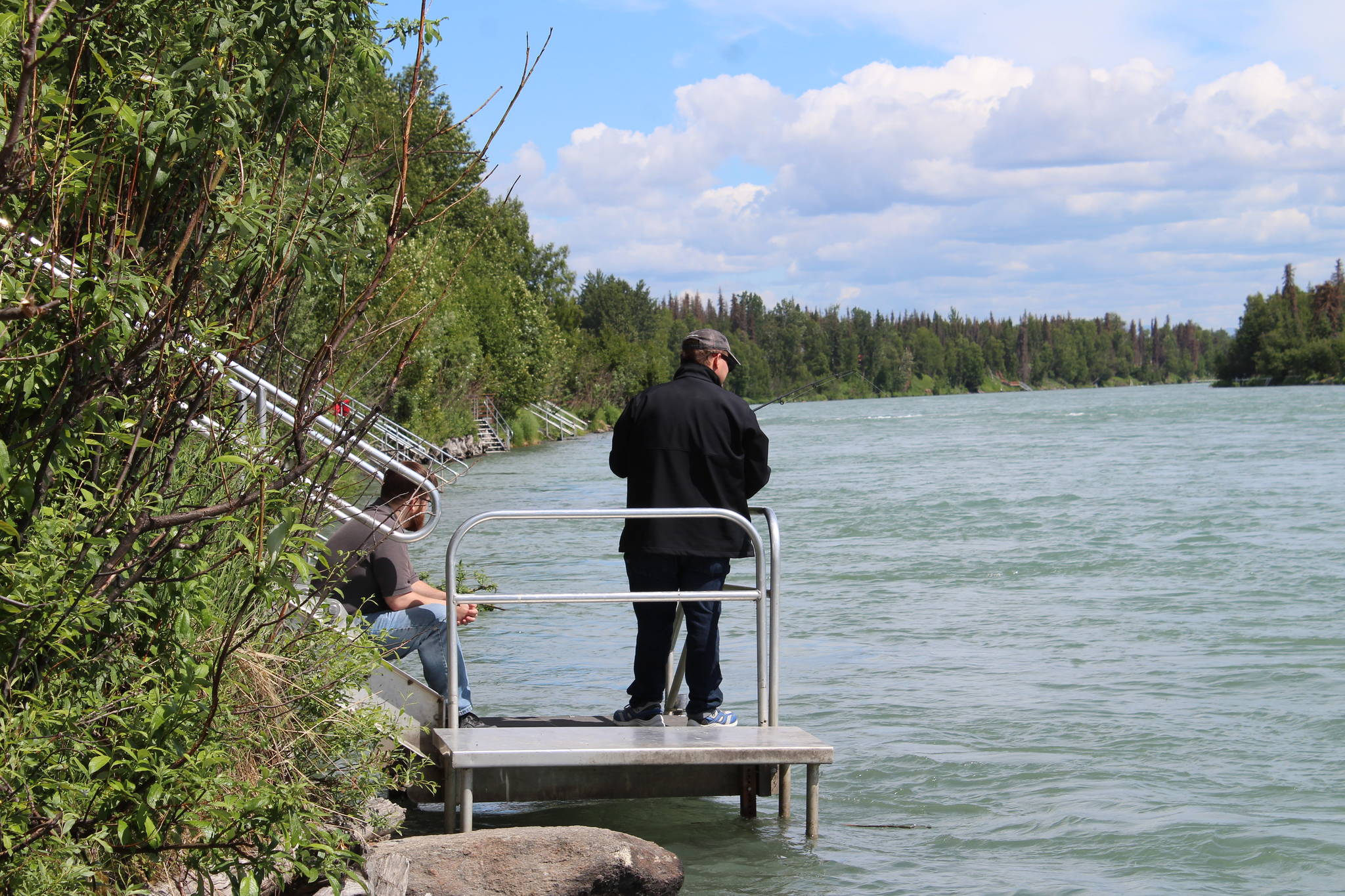 A fisher holds a reel on the Kenai River near Soldotna on June 30, 2021. (Photo by Ashlyn O’Hara/Peninsula Clarion)