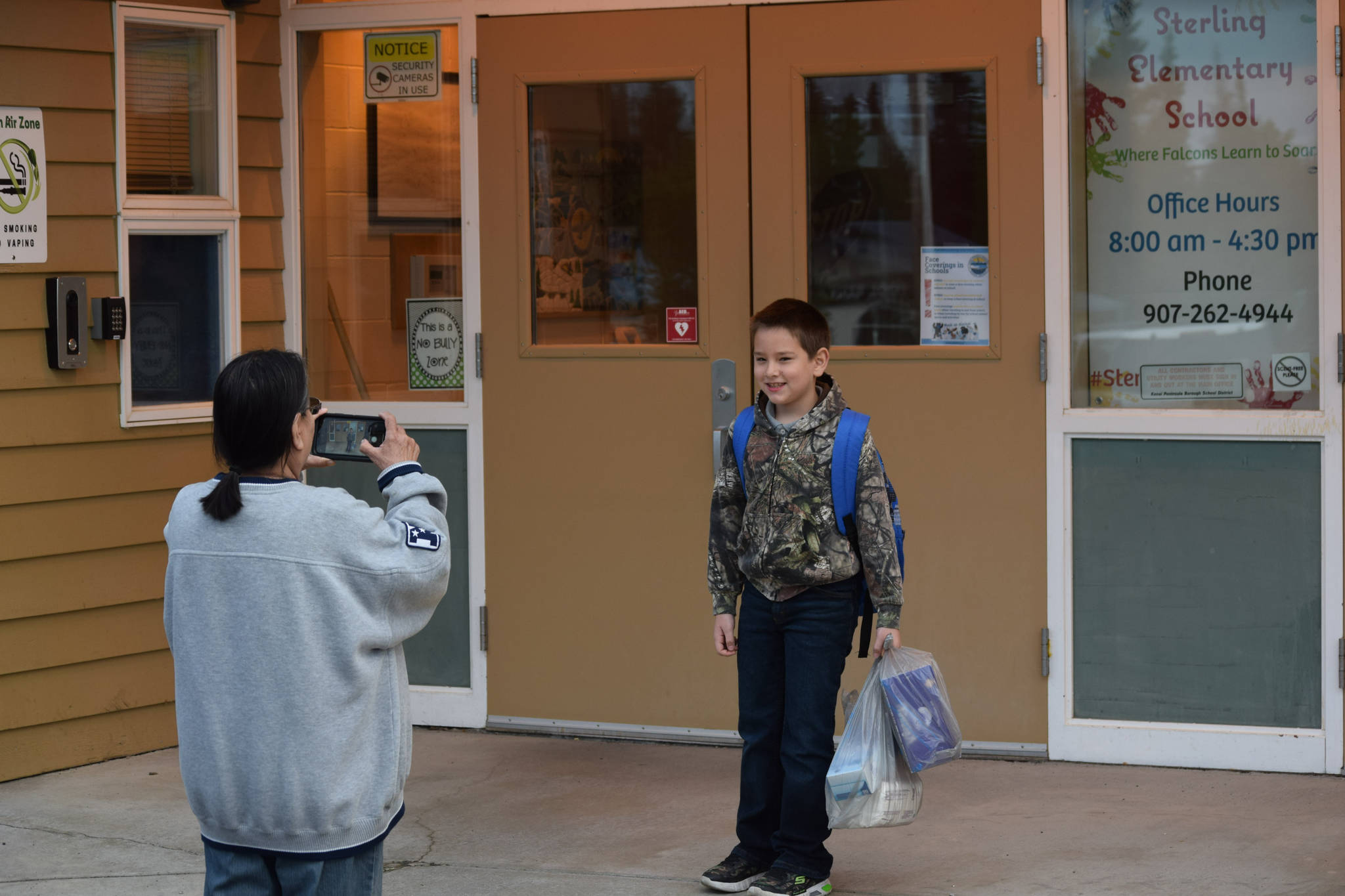 Cordy Watts takes a photo of her great-grandson Ryan Pierren on his first day of third grade at Sterling Elementary School on Tuesday, Aug. 17, 2021. (Camille Botello/Peninsula Clarion)
