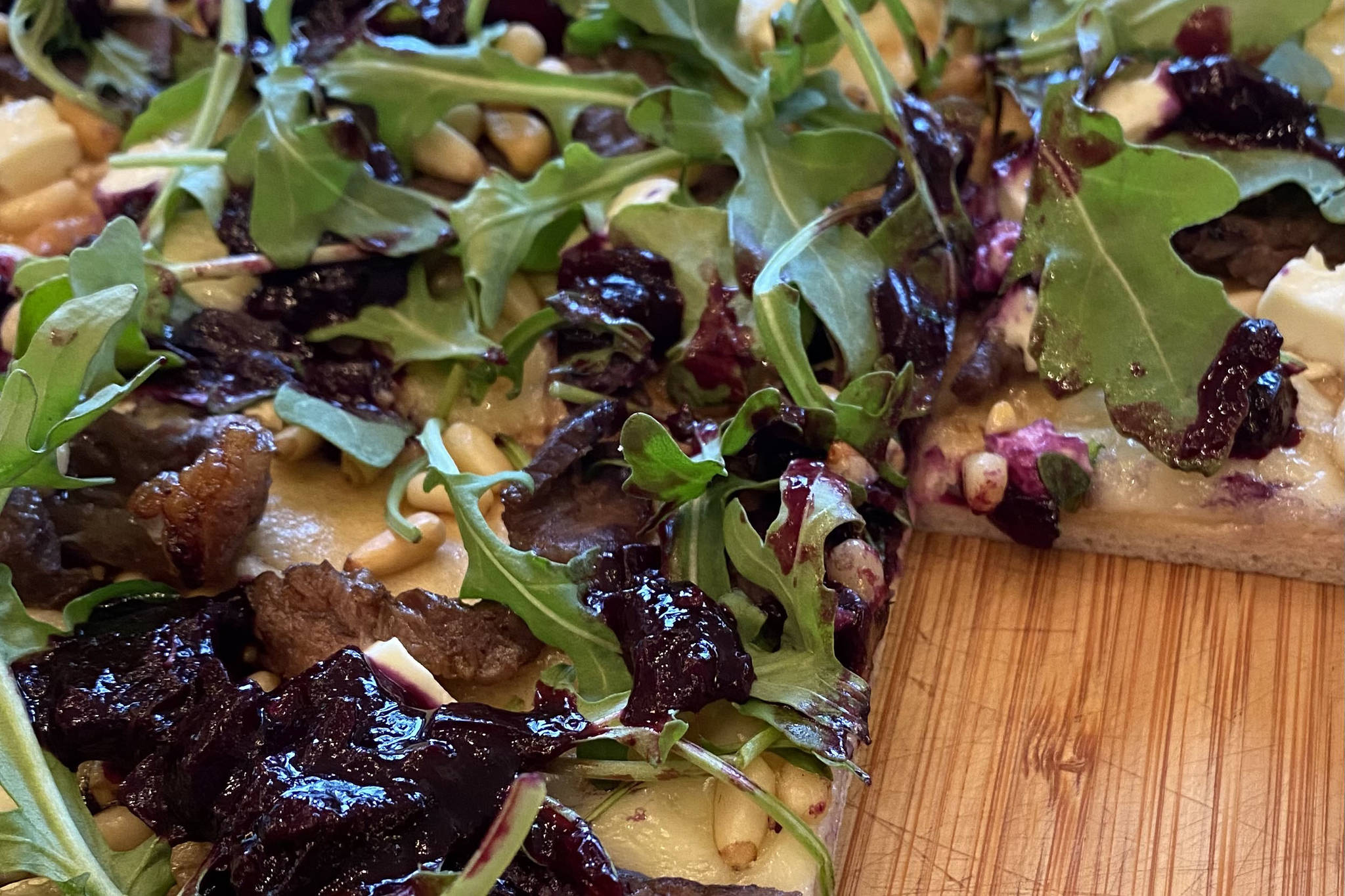 Arugula, pine nuts, and the blueberry relish top meats and homemade pizza dough. (Photo by Tress Dale/Peninsula Clarion)