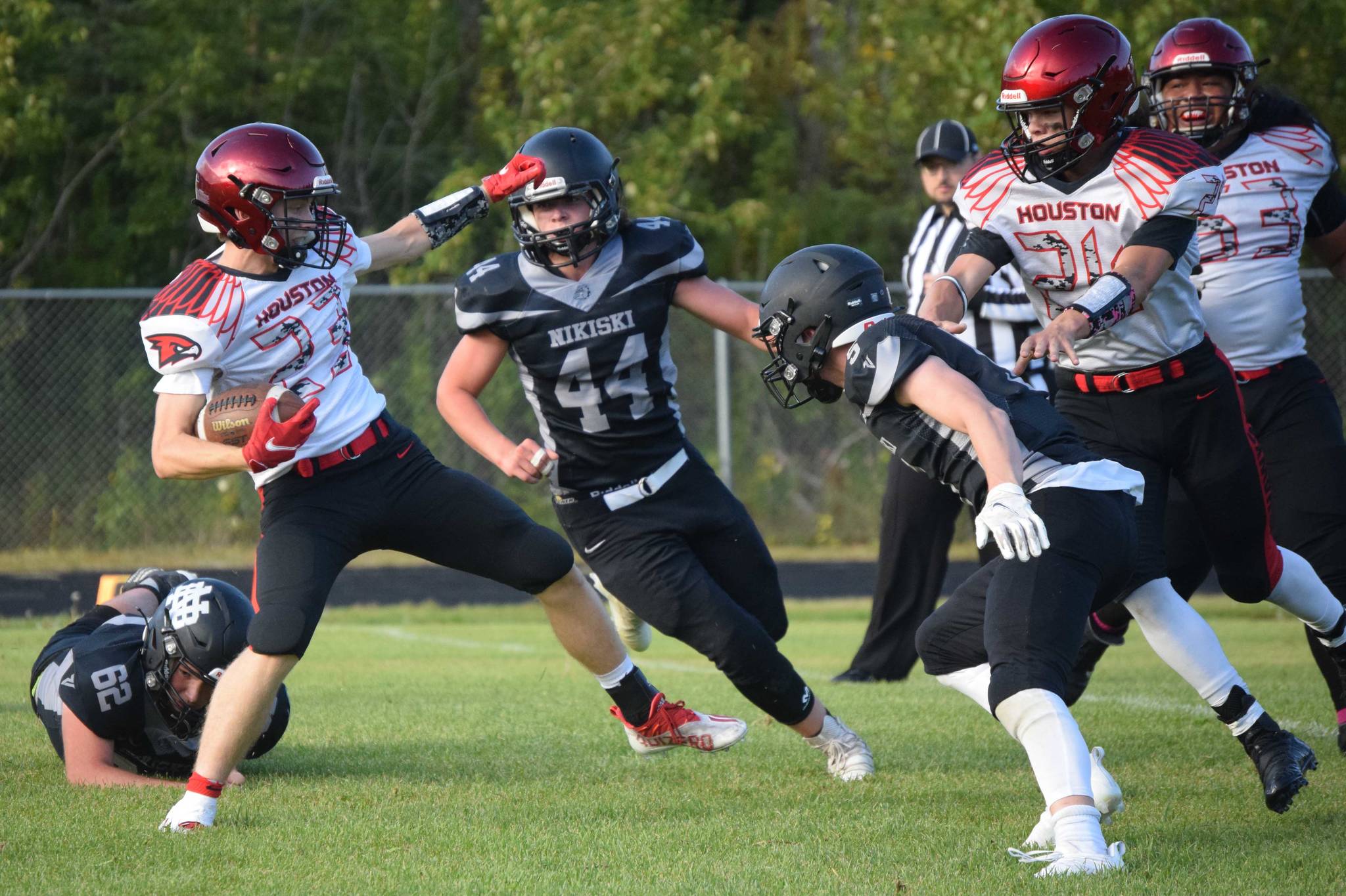 Houston running back Cody Wyrick tries to get past Nikiski's Truit McCaughey and Christian Caddock on Friday, Aug. 27, 2021, at Nikiski High School in Nikiski, Alaska. (Photo by Jeff Helminiak/Peninsula Clarion)