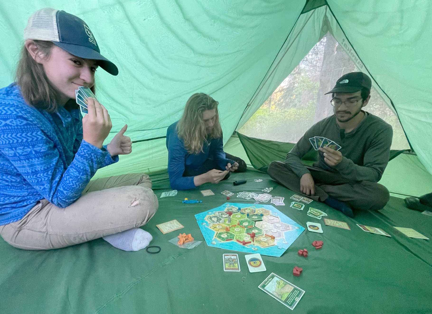 A Student Conservation Association team builds traditions around a game of Catan in a tent by Funny River. (Photo by US Fish and Wildlife Service)